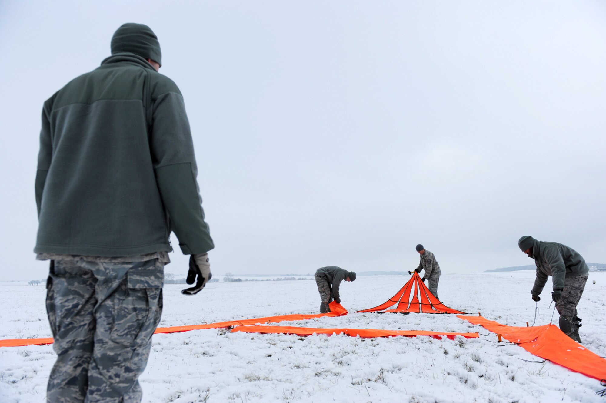 U.S. Air Force Tech. Sgt. Jason Shaffer, jump master and drop-zone safety officer, 435th Security Forces Squadron, Sembach Annex, Germany, spots as military members secure reflective panels prior to the arrival of a C-130J carrying members supporting an insertion mission, Flugplatz Bitburg, Germany, Jan. 25, 2010, in preparation of Ramstein's operational readiness inspection in September. The unit is setting up bare-base operations as part of the dual-wing operational readiness exercise with the 86th Airlift Wing. This is the second of five operational readiness exercises. (U.S. Air Force photo by Staff Sgt. Sarayuth Pinthong)
