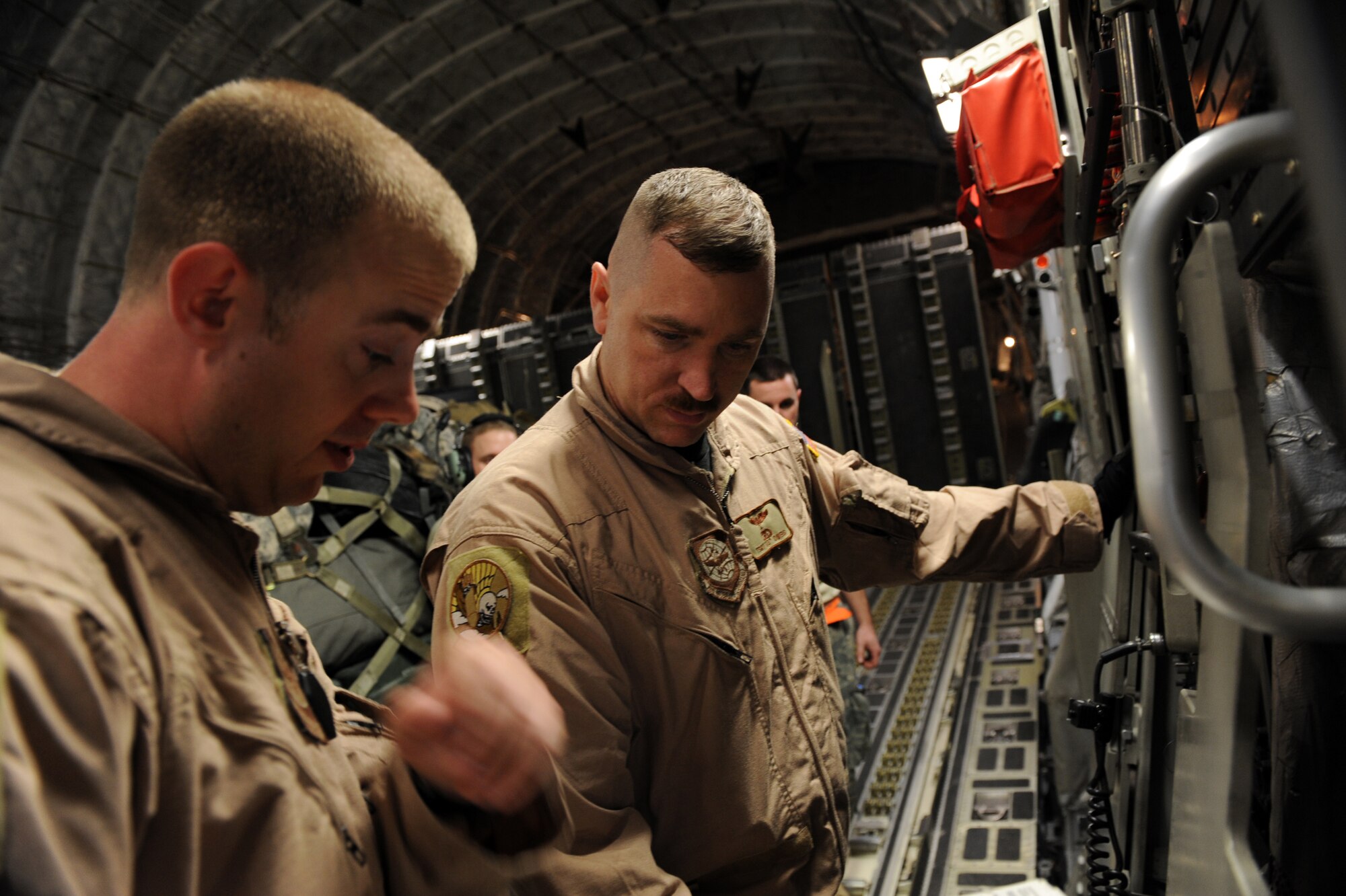 Senior Airman Anthony E. Fuller (left) and Tech. Sgt. Kevin M. Owens, both C-17A Globemaster III loadmasters assigned to the 816th Expeditionary Airlift Squadron, troubleshoot malfunctions in a C-17As loading ramp Jan. 20, 2010, at a forward operating base in Southwest Asia. (U.S. Air Force photo/Staff Sgt. Manuel J. Martinez)
