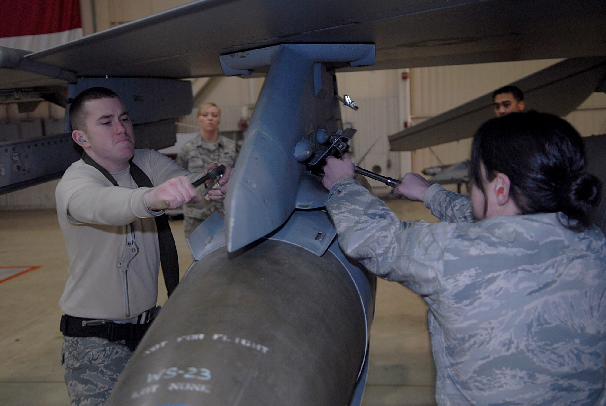KUNSAN AIR BASE, Republic of Korea -- Senior Airman Jesse Tannehill and Staff Sgt. Jennifer Diana both from the 8th Aircraft Maintenance Squadron weapons load crew member, secures a munition on an F-16 Fighting Falcon during a weapons load competition Jan. 22. A weapons load competition is held every month in order for weapons Airmen to maintain proficiency. (U.S. Air Force photo/Senior Airman Roy Lynch)