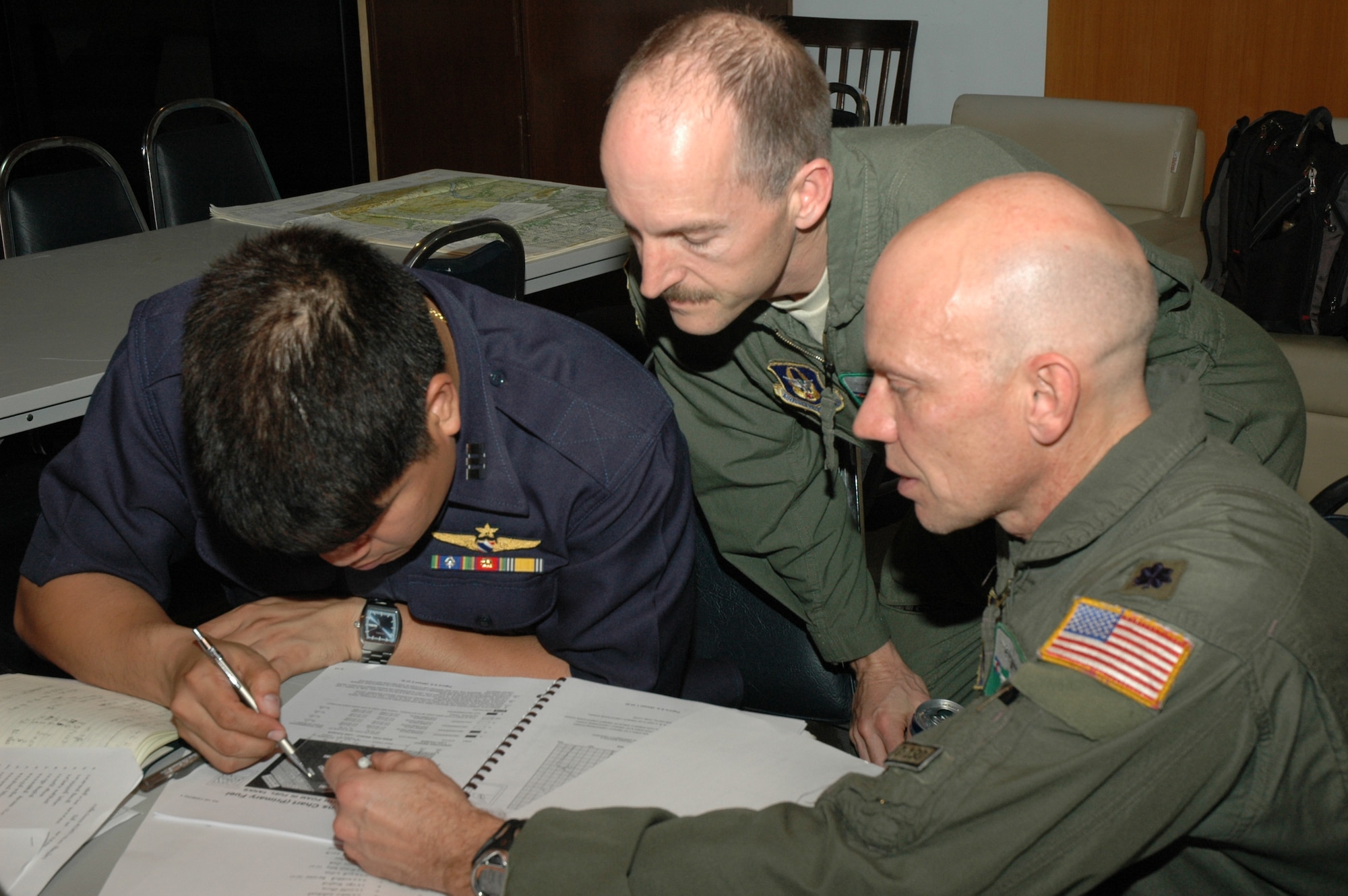 Senior Master Sgt. Kenneth E. Kunkle, flight engineer, and Lt. Col. James M. Steward, chief of flying safety, both with the 302nd Airlift Wing based at Peterson AFB, Colo., assist a Royal Thai Air Force counterpart in checking the wing stress levels in the C-130 flight manual.  Seven members of the 302 AW traveled to Thailand to provide expert training to RTAF members on safe and effective Modular Airborne Firefighting System operations.  This event marks the first time the Air Force Reserve has sent delegates to train a foreign Air Force on use of the MAFFS equipment. (U.S. Air Force photo/Capt. Jody L. Ritchie)