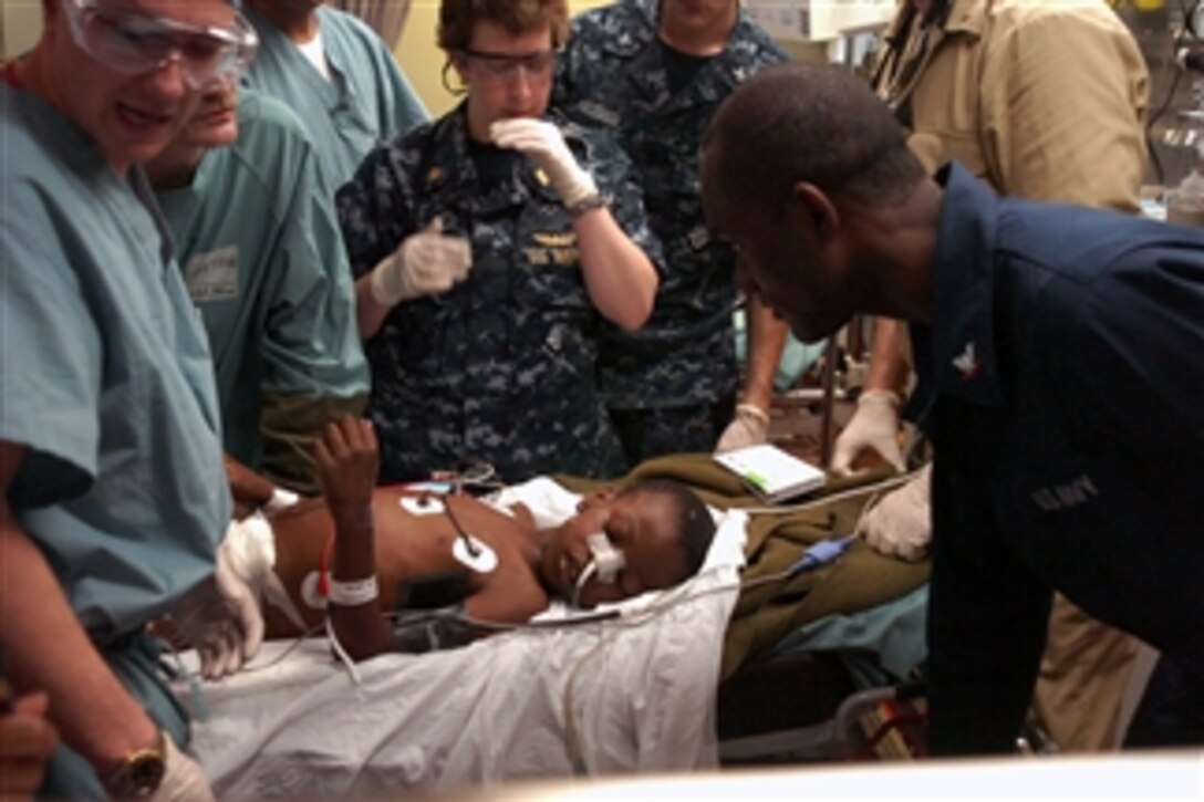 Medical personnel aboard the Military Sealift Command hospital ship USNS Comfort (T-AH 20) treat a Haitian boy in the casualty receiving room aboard the ship while underway in the Atlantic Ocean on Jan. 19, 2010.  The child was transferred to the Comfort by a helicopter from the aircraft carrier USS Carl Vinson (CVN 70) to receive treatment for injuries sustained during a 7.0-magnitude earthquake that struck Haiti on Jan. 12, 2010.  The boy, who is in the intensive care unit aboard the Comfort, is in stable condition.  