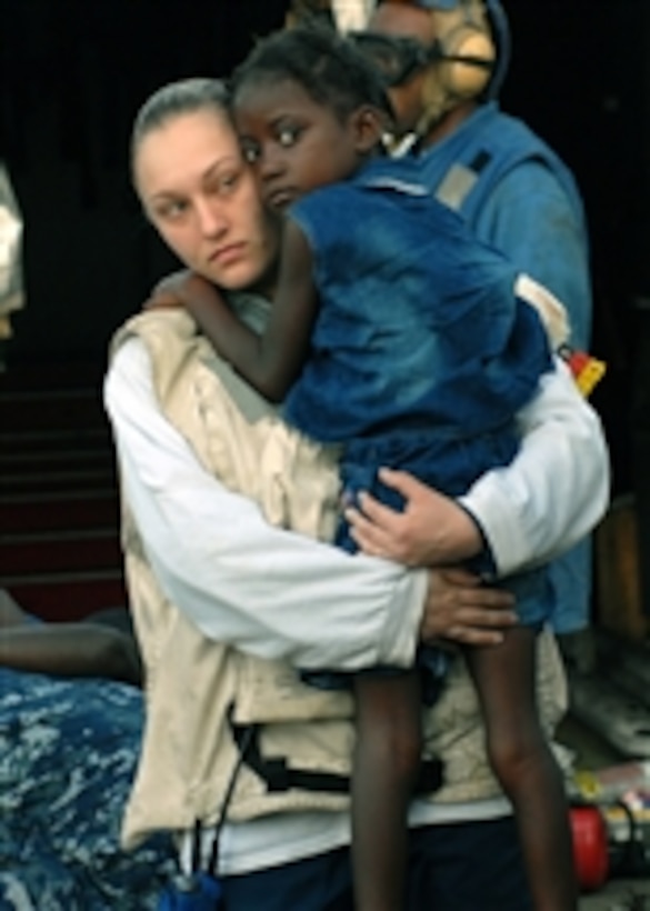 U.S. Navy Petty Officer 3rd Class Katie Blankenship carries an injured Haitian girl while aboard the amphibious dock landing ship USS Fort McHenry (LSD 43) off the coast of Haiti on Jan. 24, 2010.  The girl will be flown off the ship to receive additional medical care.  The Fort McHenry is currently participating in Operation Unified Response as part of the USS Bataan (LHD 5) Amphibious Relief Mission.  The ship is providing military support to civil authorities to help stabilize and improve the situation in Haiti.  