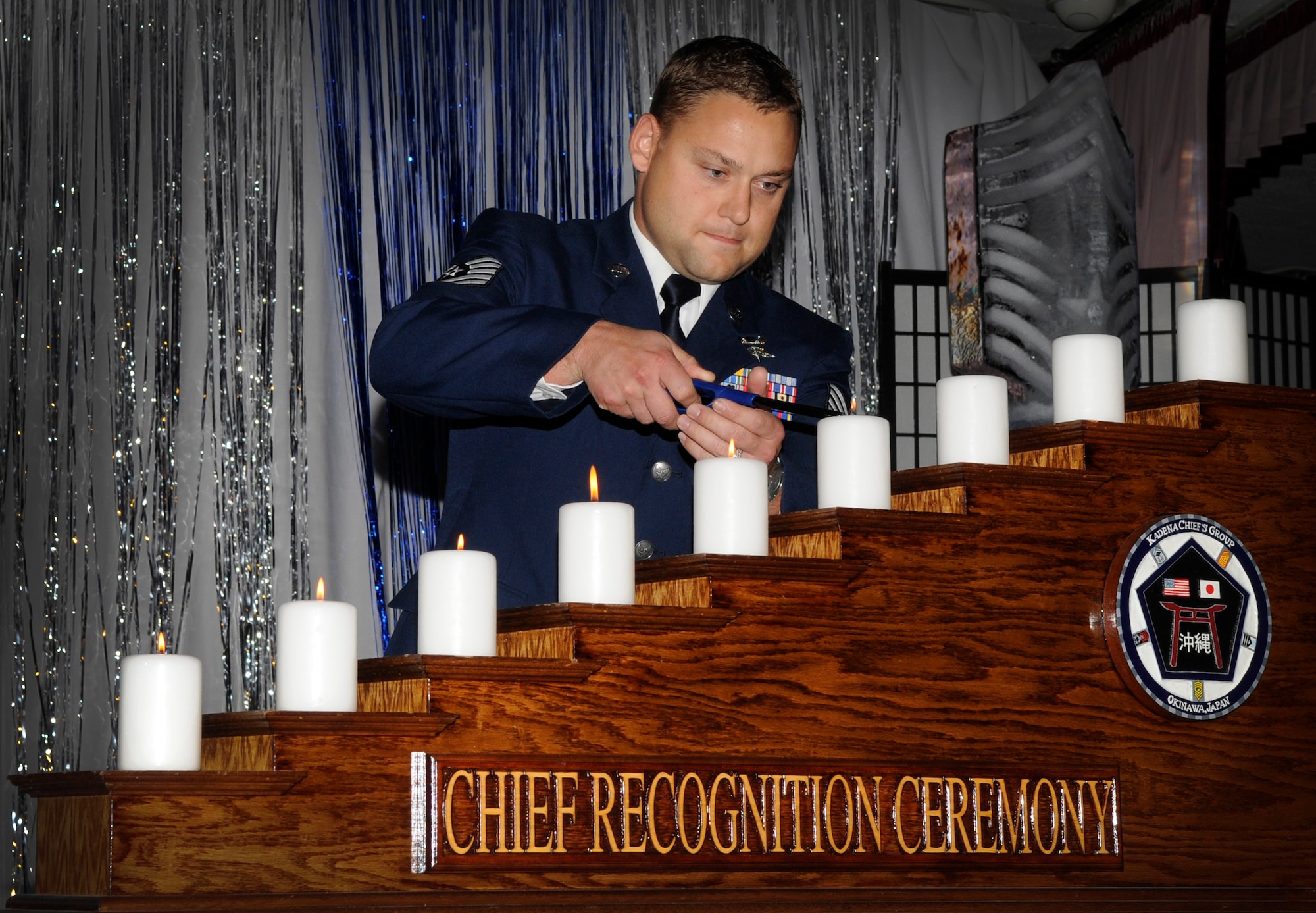 Tech. Sgt. Trevor Brinton, 31st Rescue Squadron, lights the E-6 candle representing the inductees rite of passage through the enlisted ranks of their careers during the Chiefs' recognition ceremony at the Rocker NCO Club Jan. 23. The event included a candle lighting ceremony, cake cutting ceremony and speech by Fifth Air Forces Command Chief Master Sgt. Richard Kaiser. (U.S. Air Force photo by Staff Sgt. Chrissy Best)