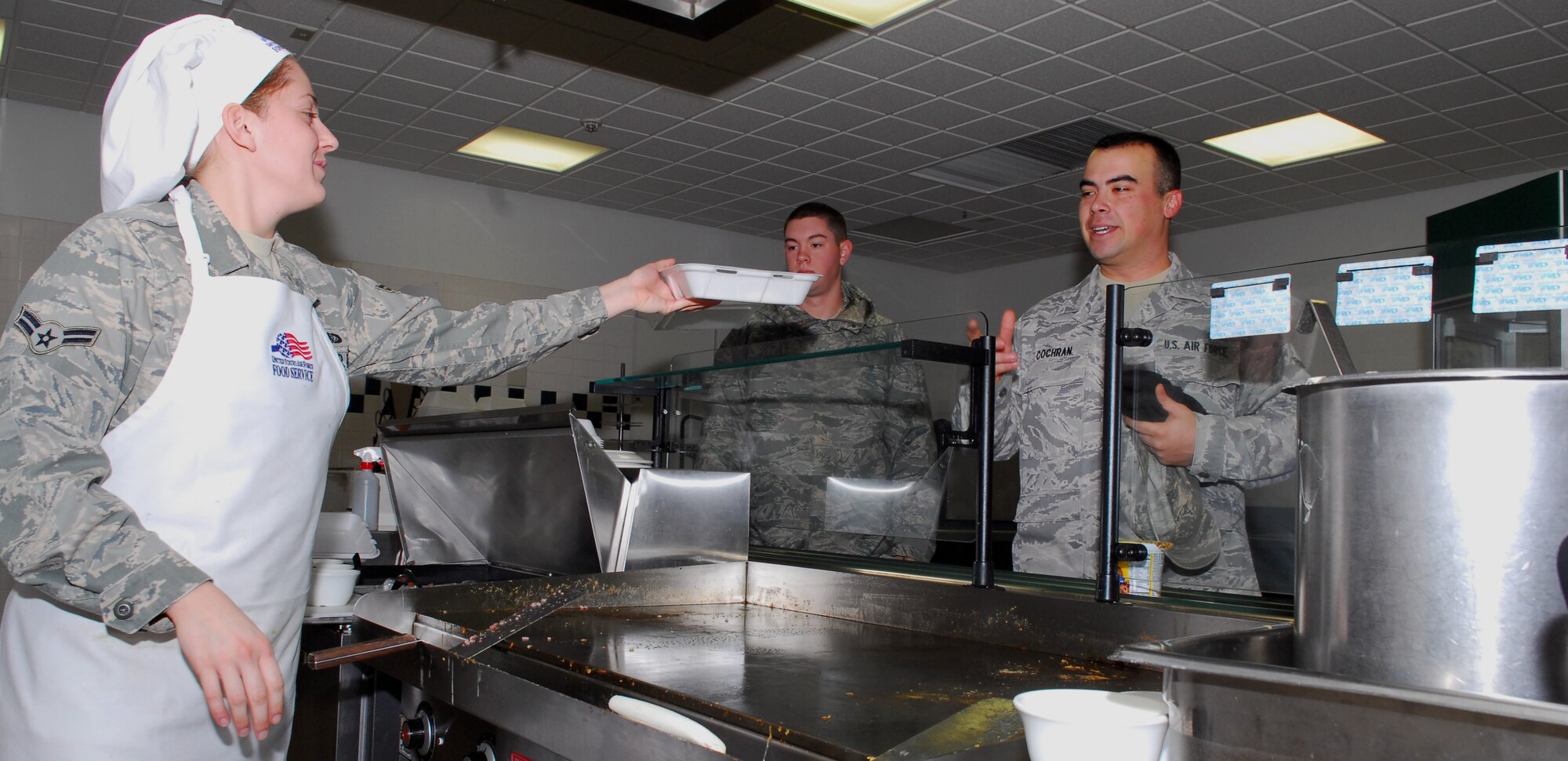MISAWA AIR BASE, Japan – Airman 1st Class Whitney Massey, 35th Force Support Squadron Grissom Dining Facility line cook, hands Airman 1st Class Justin Cochran, 35th Civil Engineer Squadron engineering apprentice, his breakfast as Airman 1st Class Robert Wesson, 35th CES heating and air conditioning apprentice, waits to place his order Jan. 26 at the Grissom Dining Facility. The DFAC will operate at regular hours during exercise Beverly Sunrise 10-01. (U.S. Air Force photo/Staff Sgt. Phillip Butterfield)