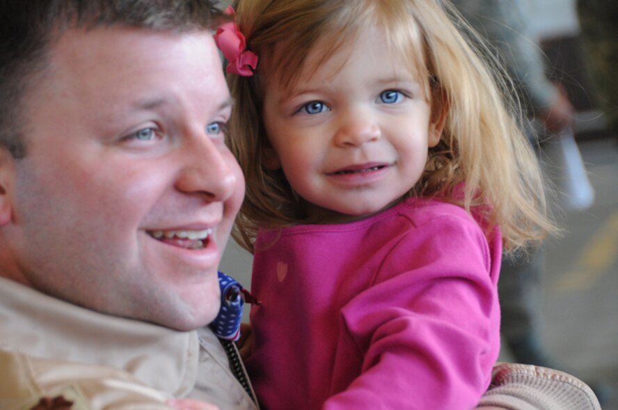 ELLSWORTH AIR FORCE BASE, S.D.-- Maj. Andrew DiNuzzo, 37th Bomb Squadron B-1 Lancer pilot, holds his daughter after arriving back home a deployment to Southwest Asia, here Jan. 27. While serving in Southwest Asia, Major DiNuzzo provided rapid, decisive and sustainable combat airpower to Operations Iraqi Freedom and Enduring Freedom. (US Air Force Photo/ Senior Airman Adam Grant)