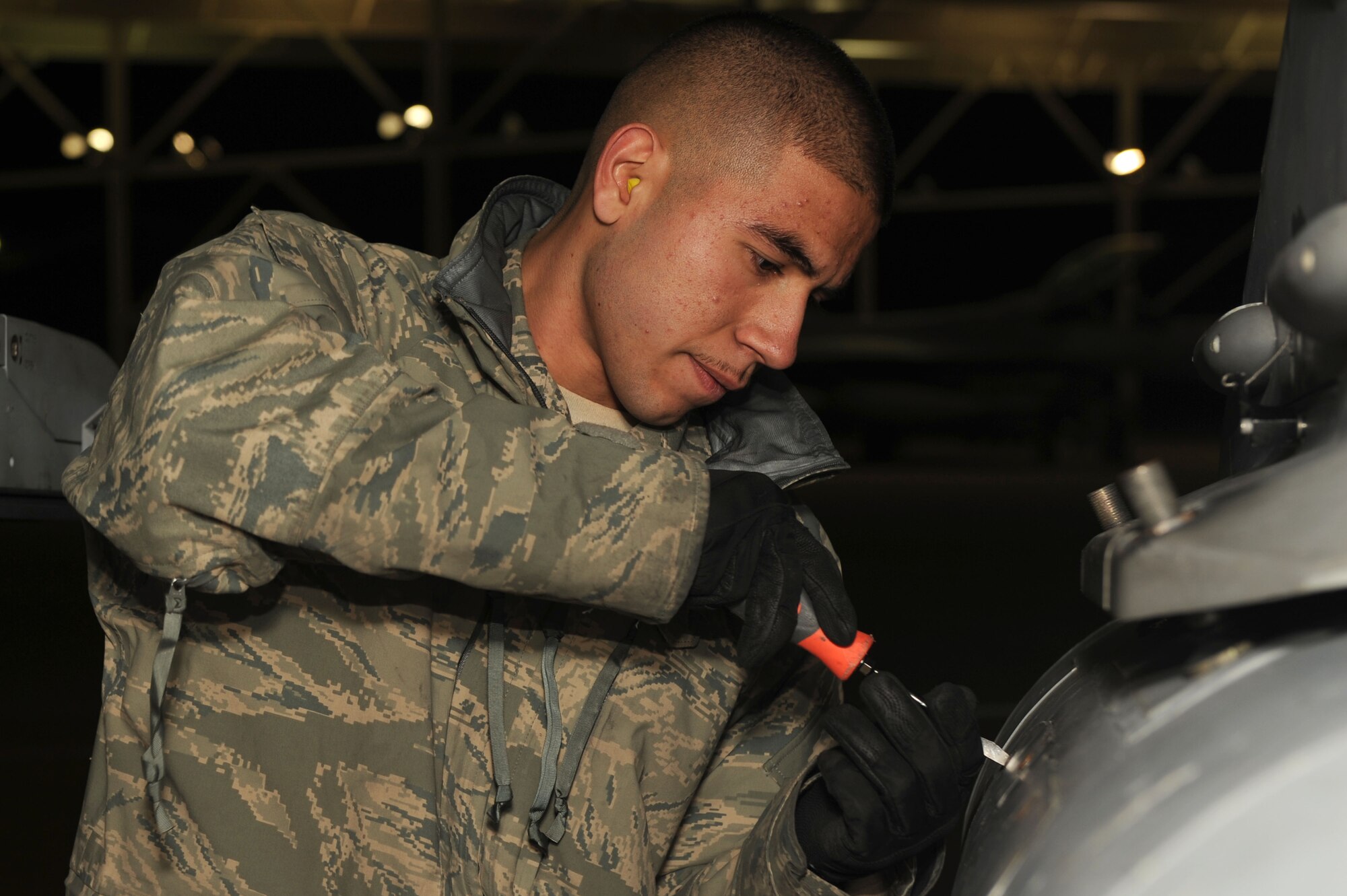 SHAW AIR FORCE BASE, S.C. -- Senior Airman Adrian Desantiago, 20th Aircraft Maintenance Squadron, tightens the screws on the panel of an F-16 fighter jet Jan. 26. The 77th Fighter Squadron "Gamblers" deployed to Iraq in support of Operation Iraqi Freedom and the Global War on Terror. (U.S. Air Force Photo/Senior Airman David Minor)