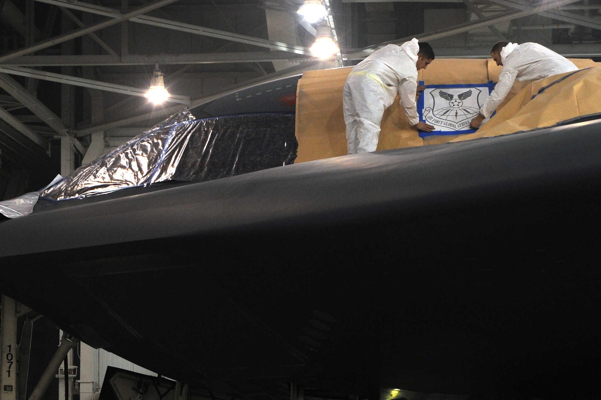 WHITEMAN AIR FORCE BASE, Mo. - Senior Airman Brian Neeley, 509th Maintenance Squadron, and Senior Airman Travis Smith, 131st Bomb Wing, structural maintenance and low-observable technicians, finish masking a B-2 before spraying on the new Air Force Global Strike Command patch to prevent over-spray, here, Jan. 27, 2010. On Feb. 1, 2010, Whiteman AFB and its arsenal of 20 B-2 bombers will change commands from Air Combat Command to AFGSC. The mission of AFGSC is to "develop and provide combat-ready forces for nuclear deterrence and global strike operations-- safe-- secure-- credible to support the President of the United States and combatant commanders." (U.S. Air Force photo by Airman 1st Class Carlin Leslie) (Released)
