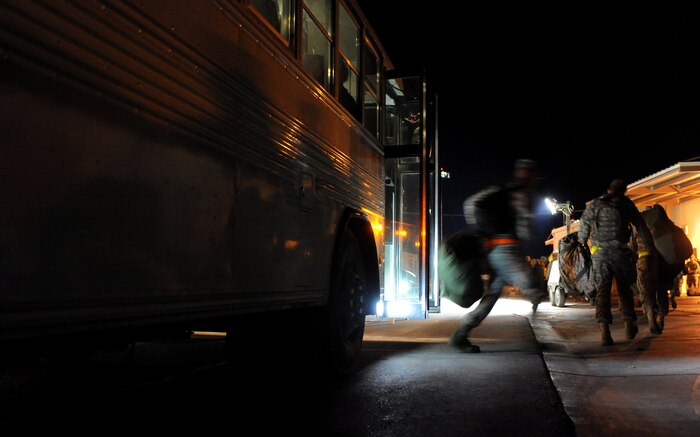 NELLIS AIR FORCE BASE, Nev. -- Airmen with mobility bags exit a bus outside the  deployment center during the 99th Air Base Wing Operation Readiness Inspection Jan. 26. (U.S. Air Force photo by Tech. Sgt. Michael R. Holzworth)
