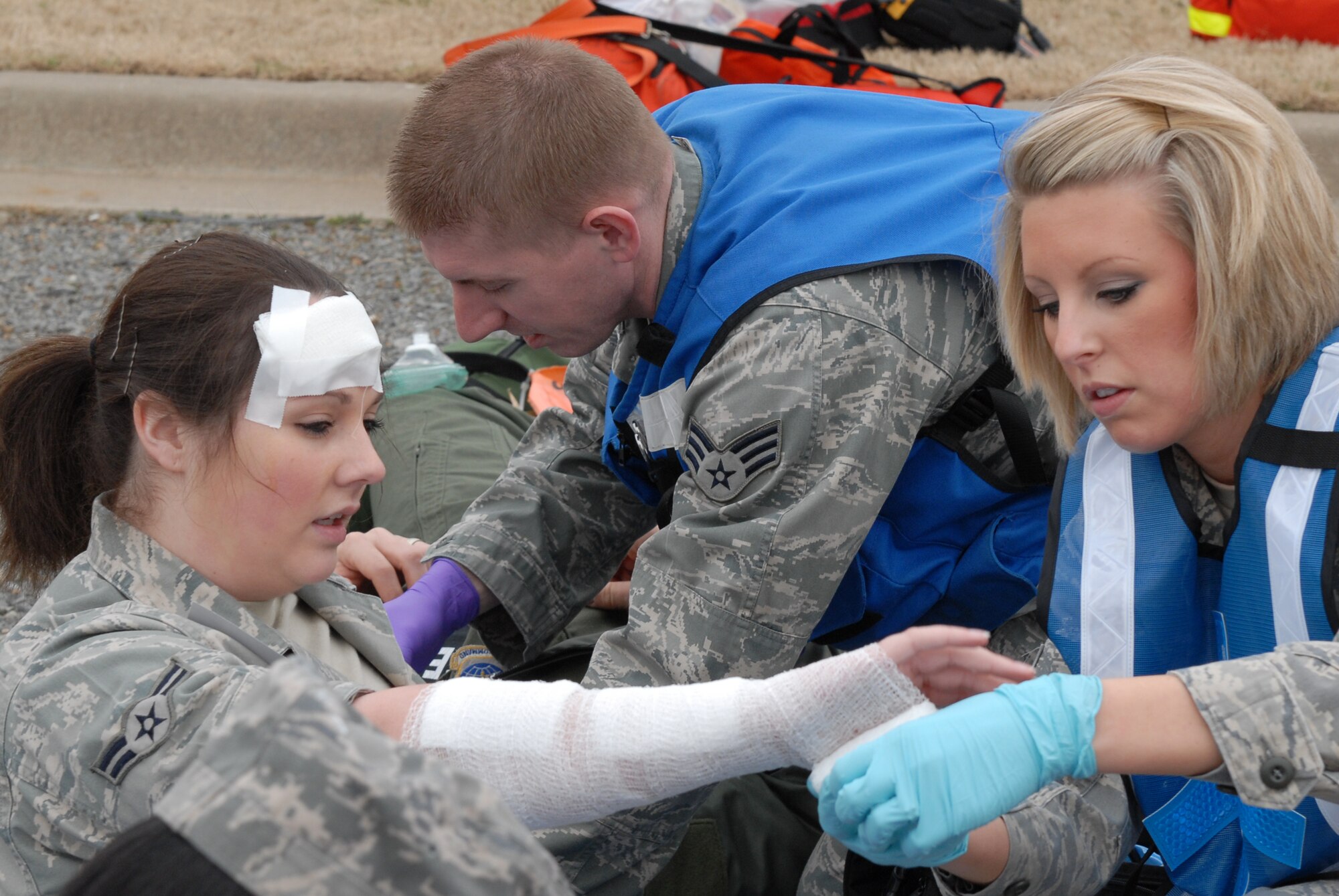 Senior Airmen Kathryn Goffe, 19th Aerospace Medicine Squadron, applies bandages to Airmen 1st Class Rachel Phillips' simulated wounds while Senior Airman Dennis Breyfogle, 19th Aerospace Medicine Squadron, tends to another patient after a simulated explosion during a major accident response exercise Jan. 22. A MARE is performed for Airmen to practice procedures that are used during a real incident. (U.S. Air Force photo by Senior Airman Christine Clark)