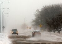 MINOT AIR FORCE BASE, N.D. -- Vehicles drive through heavy winds and snow drifts here Jan. 25. The winds reached speeds as quick as 36 mph and sustained at 35 mph. Heavy winds and snow fall created prime conditions for whiteouts. (U.S. Air Force photo by Airman 1st Class Ashley N. Avecilla)