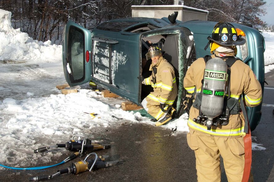 HANSCOM AIR FORCE BASE, Mass. – Firefighter Eric Naylor passes critical information to his on scene partner advising on what equipment they’ll need to safely extract the “victim” trapped in this overturned vehicle.  This exercise scenario was one of three that took place during the Base Readiness Exercise conducted here Jan. 19 to 21.  (U.S. Air Force photo by Rick Berry)