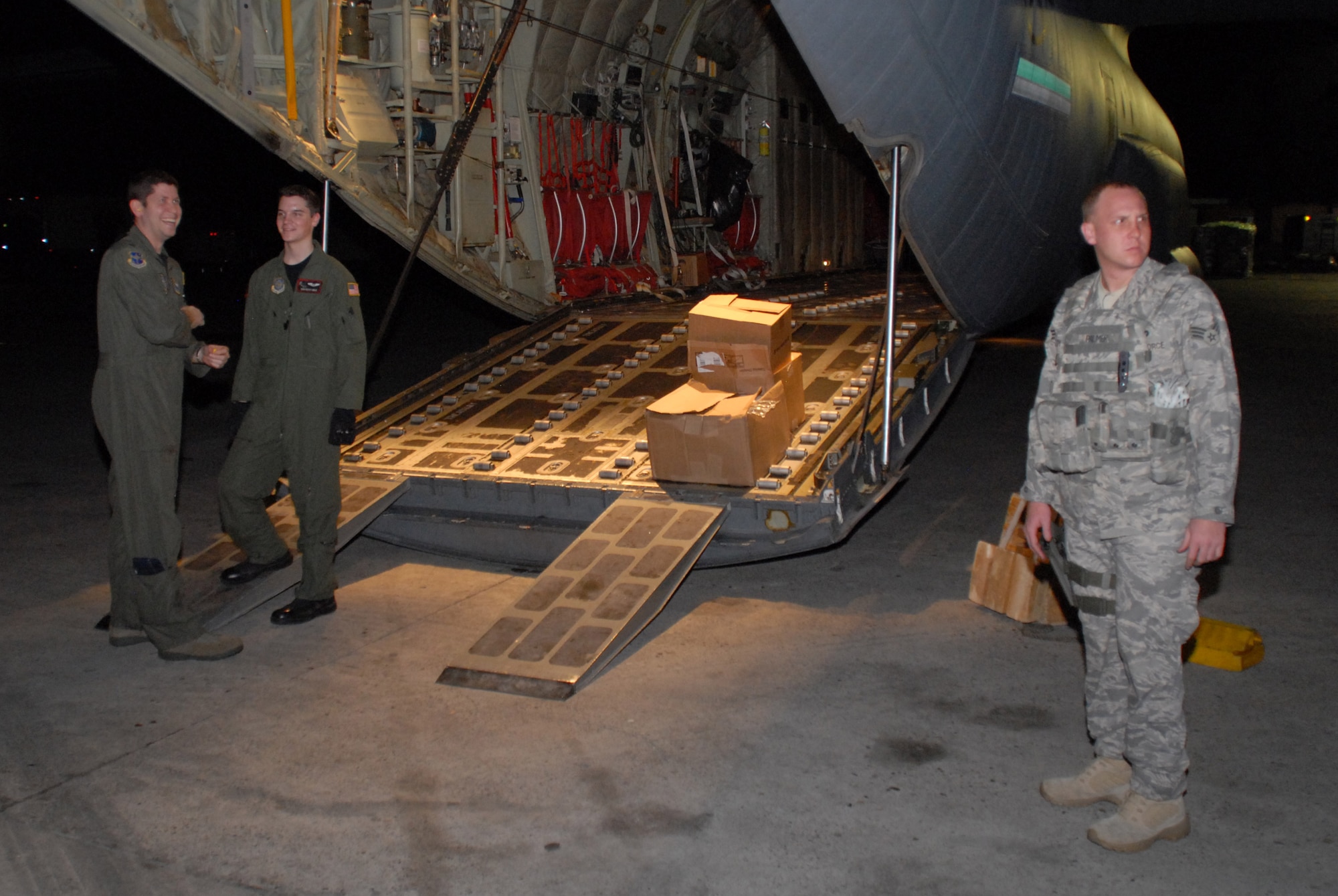 Senior Airman Steven Able, 41st Airlift Squadron loadmaster, and Capt. Cory Waldroup, 19th Operations Group pilot, await clearance to depart Port-au-Prince International Airport, Haiti Jan. 20, while a Fly Away Security Team  Security Forces Airman from Pope Air Force Base provides security.  The crew flew their C-130J into Haiti to deliver medical supplies, Army Rangers and an Army Humvee in support of Operation Unified Response, a relief effort to help the victims of the recent earthquake in Haiti. (U.S. Air Force photo by Capt. Joe Knable)