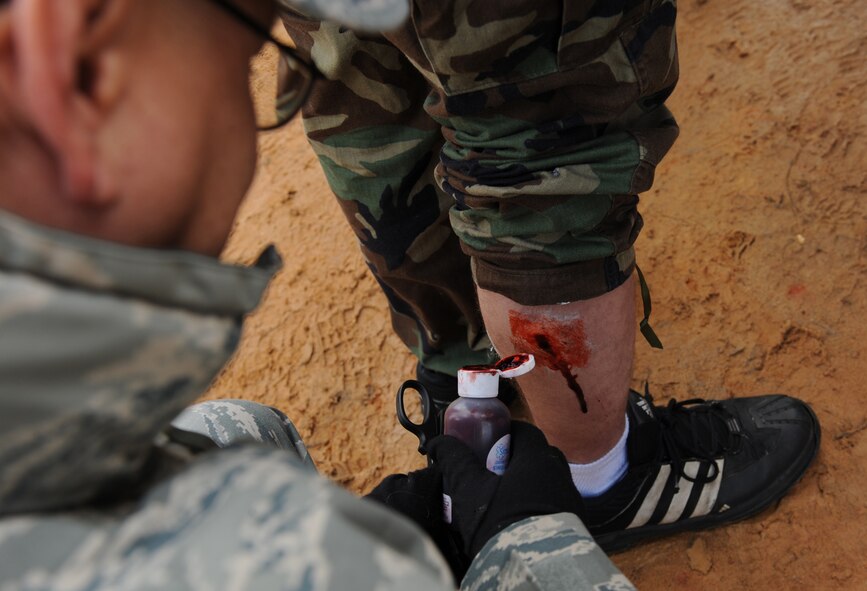 MOODY AIR FORCE BASE, Ga. -- Tech. Sgt. Roong Burket, 347th Operations Support Squadron independent duty medical technician, applies fake blood to a volunteer’s leg to simulate a gunshot wound prior to a mass casualty exercise at Spence Air Field in Moultrie, Ga., Jan. 25. Sergeant Burket also used cotton balls, glue and make-up to simulate a wide variety of injuries. (U.S. Air Force photo by Airman 1st Class Benjamin Wiseman)