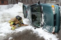 HANSCOM AIR FORCE BASE, Mass. – Hanscom firefighter Eric Naylor prepares to stabilize an overturned van before fellow firefighters move in to rescue victims during this portion of the base readiness exercise Jan. 19 to 21.   Stabilizing the vehicle with wood shims prevents the vehicle from rolling any further allowing rescue personnel to safely work to remove any trapped occupants.    (U.S. Air Force photo by Rick Berry) 