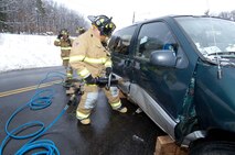 HANSCOM AIR FORCE BASE, Mass. - Hanscom firefighter Eric Naylor operates the Jaws of Life to rescue a passenger from one of two vehicles involved in a “staged” two car collision here.  The rescue was one of three Base Readiness Exercise scenarios conducted as part of the three day base readiness exercise conducted Jan. 19 to 21.  Firefighters Andrew Lebel and Patrick Kelly (background) provide line support during the operation.     (U.S. Air Force photo by Rick Berry)