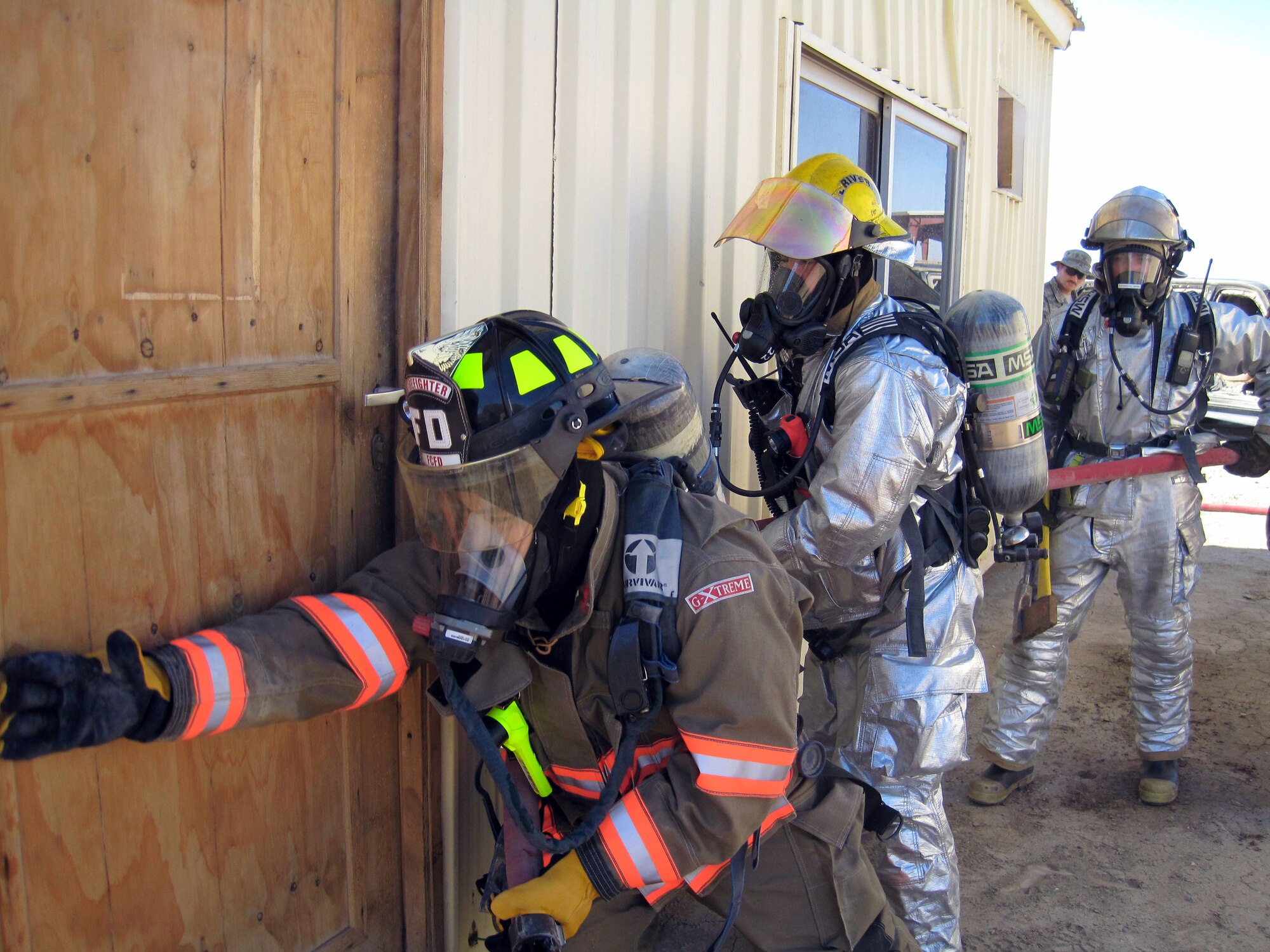 U.S. Army Specialist Edgar Acena, 60th Ordinance Company, U.S. Air Force Senior Airman Shaun Heil, and Senior Airman Kyle Parson, 407th Expeditionary Civil Engineer Squadron check the doorway for heat before making an entry into a training trailer as part of a Fire Officer I practical here, Ali Base, Iraq Jan. 23, 2010.  The objective of the Fire Officer I practical was to respond and take Incident Command of an emergency.  (US Air Force photo by Staff Sgt Miguel Lara III/Released.)