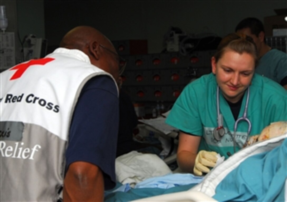 U.S. Navy Lt. Lindsay Touchette (right) cares for a burn victim in an intensive care unit ward aboard Military Sealift Command hospital ship USNS Comfort (T-AH 20) with the help of Alex Alexis, an American Red Cross translator, off the coast of Port-au-Prince, Haiti, on Jan. 24, 2010.  The Comfort is supporting Operation Unified Response in the wake of the 7.0-magnitude earthquake that hit Haiti on Jan. 12, 2010.  