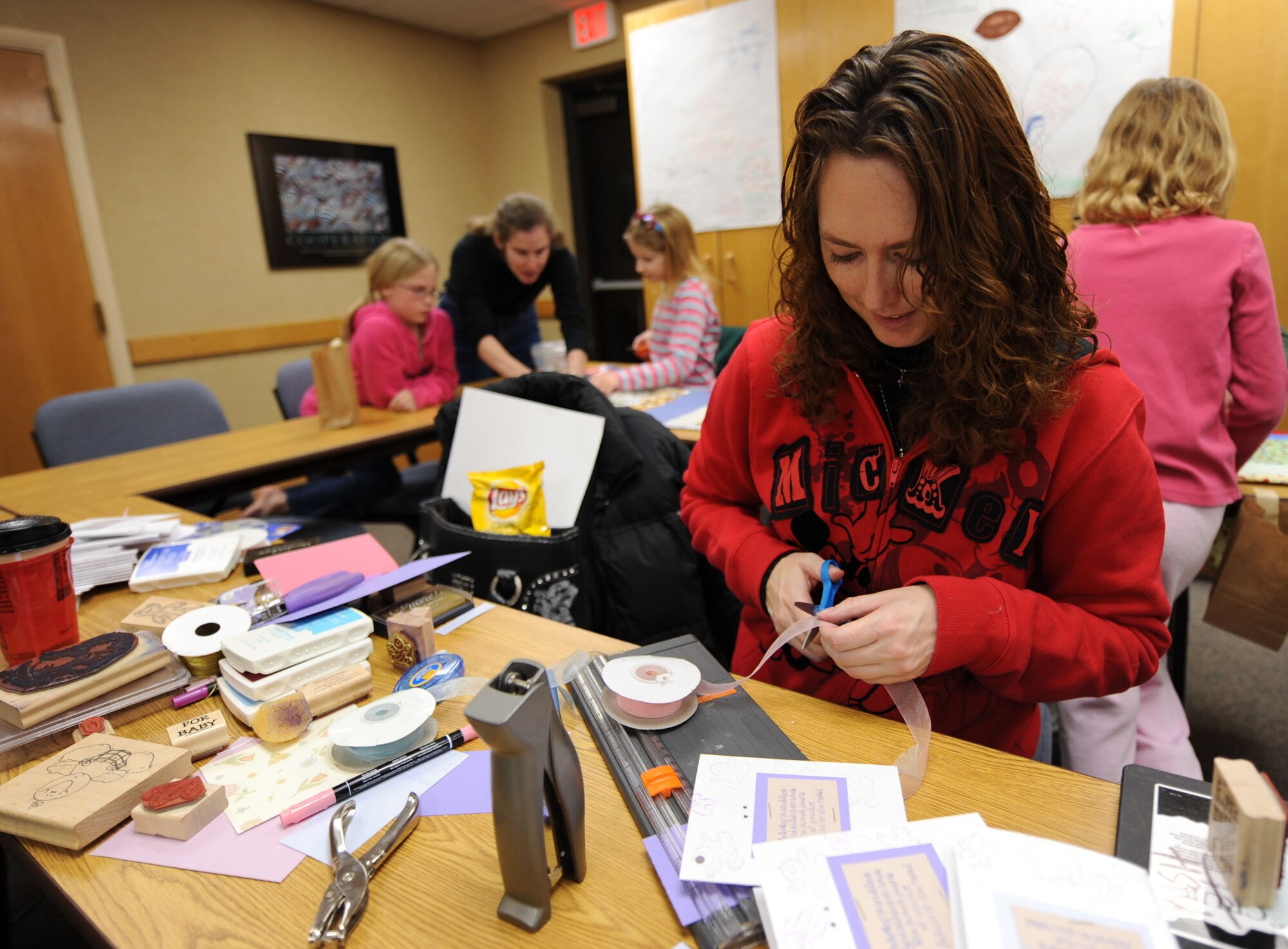 MOUNTAIN HOME AIR FORCE BASE, Idaho -- Kim Kish cuts ribbon to assemble cards during Hammond Quilt Day at the 366th Force Support Squadron Airman and Family Readiness Center Jan. 23. Volunteers assembled approximately 40 crocheted blankets, hats and cards into individual bundles to donate to families with newborn babies. (U.S. Air Force photo by Airman 1st Class Renishia Richardson)