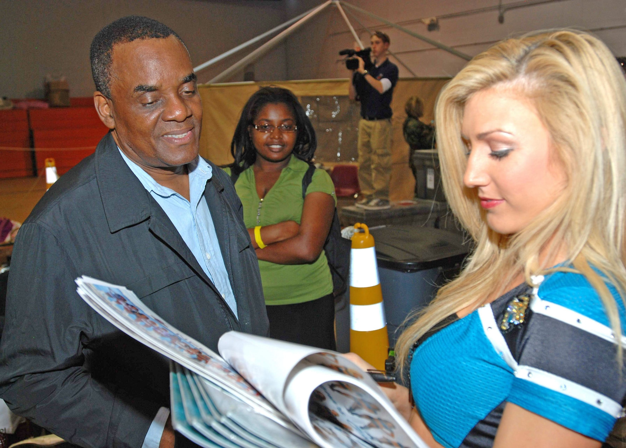 A Jacksonville Jaguars cheerleader signs an autograph for Cadet Pierre-Paul Jan. 27, 2010, at Homestead Air Reserve Base. Mr. Pierre-Paul is among 3,000 evacuees who've processed through Homestead ARB. National Football League cheerleaders and mascots selected to participate in the Pro Bowl visited the base to meet with relief workers and evacuees. (U.S. Air Force photo/Tech. Sgt. Brian Bahret)