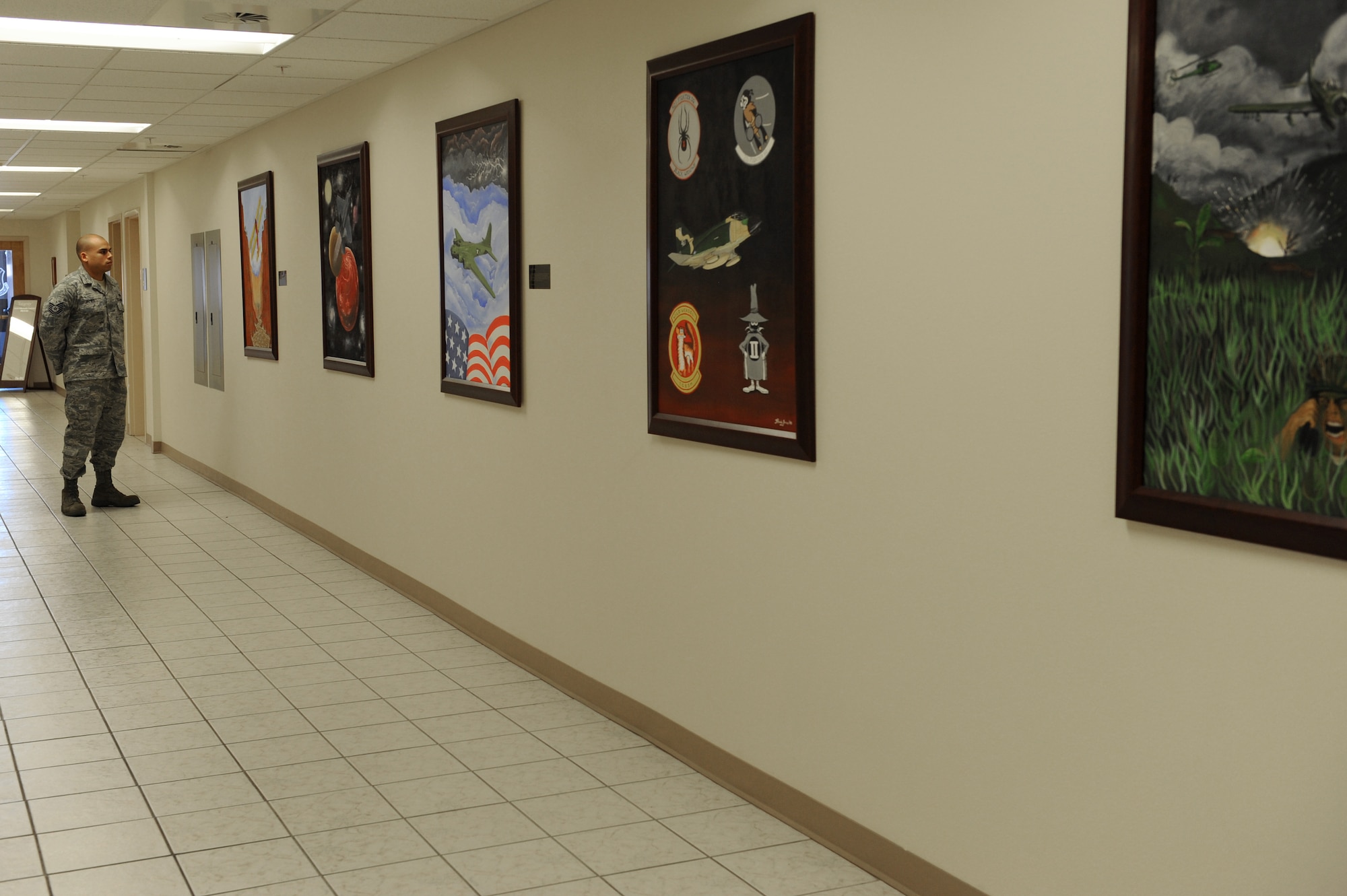 Tech Sgt. Randy James, 57th Maintenance Group quality assurance inspector, admires the first of five paintings he created for the Nellis Airman Leadership School Jan. 28. Sergeant James was asked to create five mural paintings placed on the wall leading to the Heritage Room at the Nellis ALS.( U.S. Air Force photo by Taylor Worley)