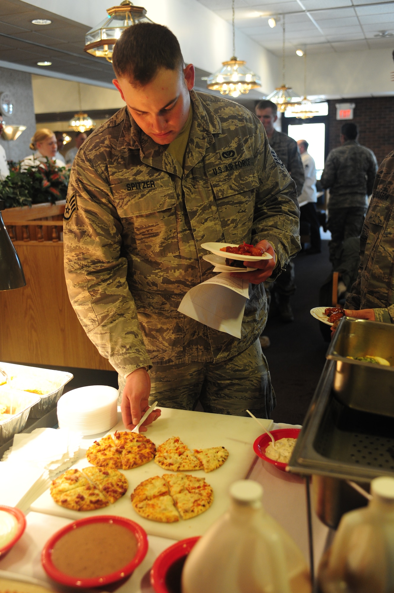 ELLSWORTH AIR FORCE BASE, S.D. -- Staff Sgt. Evan Spitzer, 28th Civil Engineer Squadron electrical systems journeyman, takes a slice of freshly made flat-bread pizza during a taste-testing event at the Bandit Inn Dining Facility, Jan 27.  The Bandit Inn hosted a taste-testing event for Airmen to help them create a new menu. (U.S. Air Force photo/Airman 1st Class Anthony Sanchelli)
