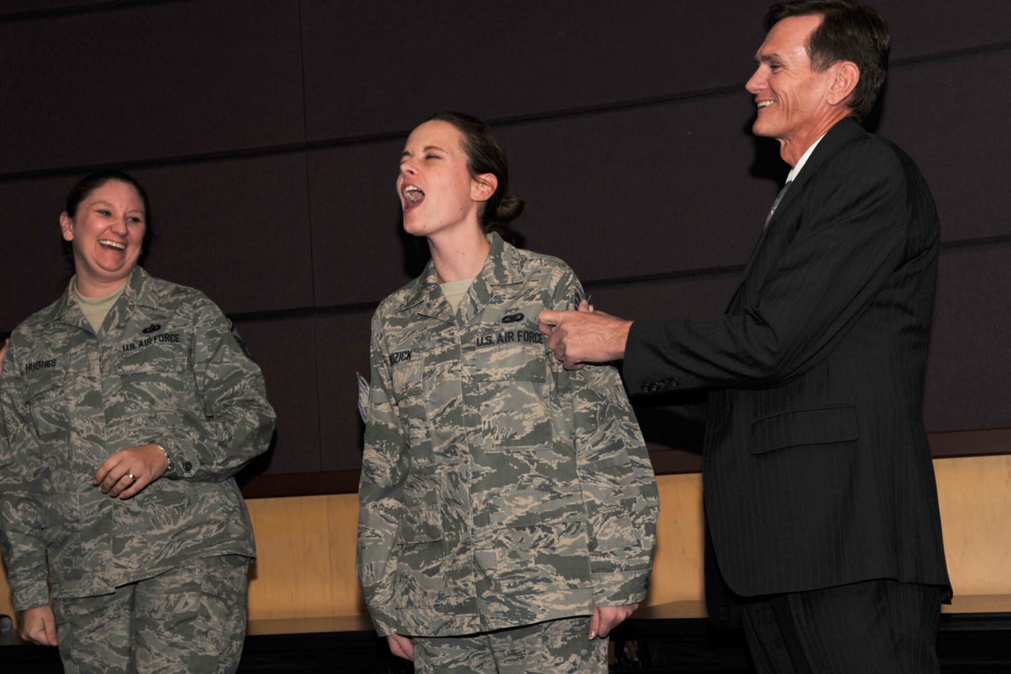 Tech. Sgt. Crystal Bozick feels the aftershocks of Master Sgt. Shannan Hughes (on left) adding new stripes to her arm during a promotion ceremony at McConnell Air Force Base, Kan., in January 2010. Sergeant Bozick's father, retired Air Force Master Sgt. Ray Willis, put new technical sergeant stripes on her other arm. (U.S. Air Force photo/Master Sgt. Jason Schaap)