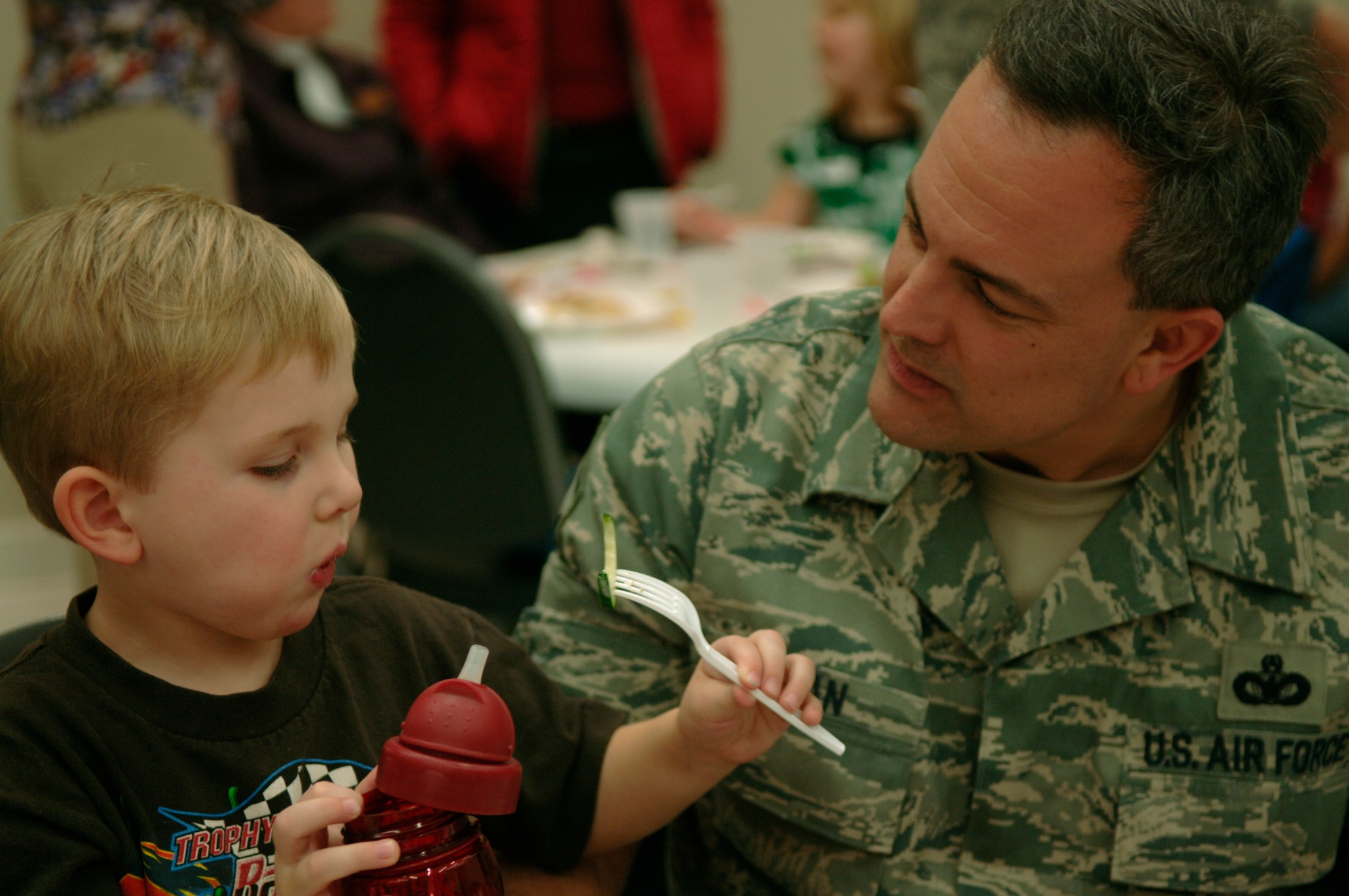Master Sgt. Jeffrey Tynan coaxes his son Chance into eating a bite of cucumber at the Quarterly Spouse Appreciation Dinner for spouses of deployed members hosted by the base chapel and Airman and Family Readiness Center Jan. 28. Sergeant Tynan was accompanied by his wife Emily, daughter Jasmine and son Chance who attended to provide moral support for the spouses and families with deployed members. Sergeant Tynan is the 437th Operations Support Squadron first sergeant. (U.S. Air Force Photo/Airman 1st Class Lauren Main)