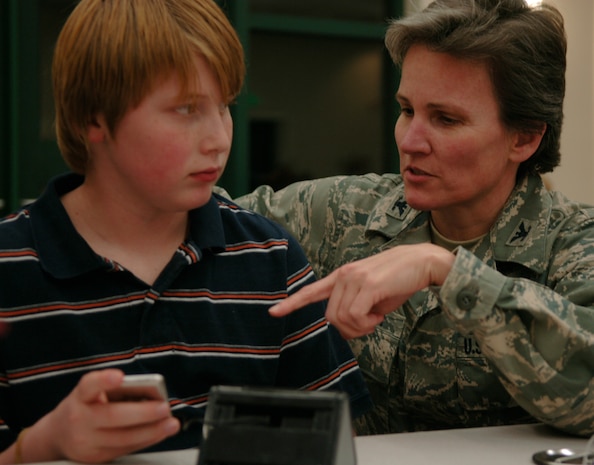 Col. Martha Meeker inquires about about Peter Tufts' iPod at the Quarterly Spouse Appreciation Dinner for spouses of deployed members at the base chapel Jan 28. The dinner was hosted by the Airman and Family Readiness Center and the base chapel to help the spouses of deployed family members connect and support one another. Peter Tufts is the son of Maj. Adam Tufts, a pilot with the 14th Airlift Squadron who is currently deployed to the Middle East with the 14th Airlift Squadron, and Colonel Meeker is the commander of the 628th Air Base Wing. (U.S. Air Force Photo/Airman 1st Class Lauren Main)