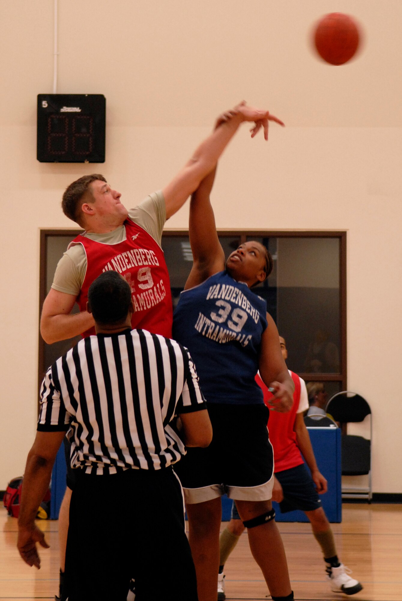 VANDENBERG AIR FORCE BASE, Calif. -- Starting the game, Paul Vignola and Lillian Street leap for the ball during an intramural basketball game at the Vandenberg Fitness Center here Thursday, Jan. 28, 2010. The 30th Operations Group battled against the Lady Hawks, winning 57-23. (U.S. Air Force photo/Senior Airman Andrew Satran) 

 