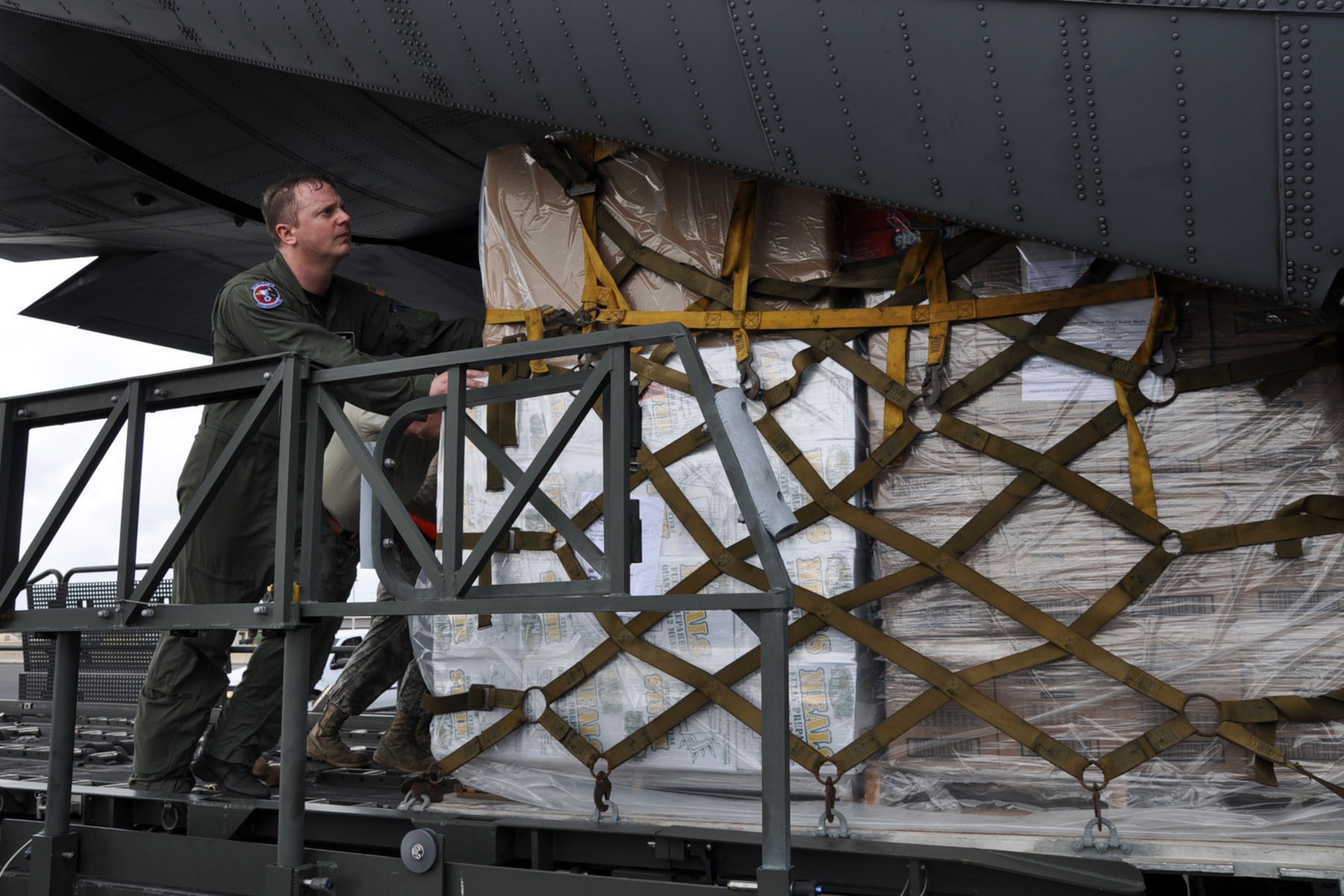 HOMESTEAD AIR RESERVE BASE, Florida -- U.S. Air Force Reserve Master Sgt. Dan Marhulik, a loadmaster assigned to the 910th Airlift Wing, works with a group of Air Force personnel to push a pallet of ready-to-eat meals onto the rear cargo ramp of a C-130H Hercules cargo aircraft on the flightline here, January 21. The pallet is part of a cargo of 18,400 pounds of food and water that the aircraft, based at Youngstown Air Reserve Station, Ohio, will carry to San Isidiro Air Base, Dominican Republic, where it will be trucked across the island to Port-au Prince, Haiti as part of the massive international effort to provide relief to the people of the Caribbean island nation in the aftermath of a devastating January 12 earthquake. U.S. Air Force photo by Master Sgt. Bob Barko Jr.