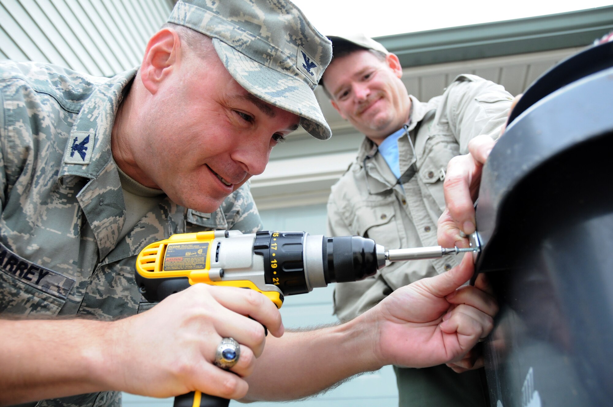 Col. David Maharrey, 96th Civil Engineer Group commander, installs "bear latches" while Andrew Jernigan, Florida Fish and Wildlife Conservation, assists on garbage cans in the Poquito Bayou housing area, Jan. 29 at Eglin Air Force Base. Volunteers from the 96th CEG are installing the latches on every garbage can in housing in hopes of discouraging bears from using the trash as a food source that will keep them coming back. In addition to the latches, the volunteers are also going door-to-door distributing information on methods to prevent bears from returning. All housing residents should have the latches installed within the next few weeks. (U.S. Air Force photo/ Airman 1st Class Anthony Jennings)
