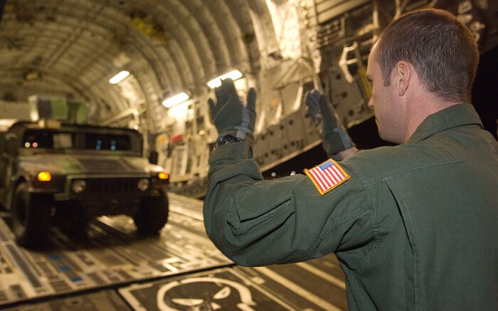 Master Sgt. Troy Firzlaff marshals a high mobility multipurpose wheeled vehicle onto a Charleston Air Force Base C-17 Jan. 28. The HMMWV will be used to support humanitarian relief efforts in Haiti. Sergeant Firzlaff is a member of the 15th Airlift Squadron. (U.S. Air Force photo/Staff Sgt. Barry Loo)