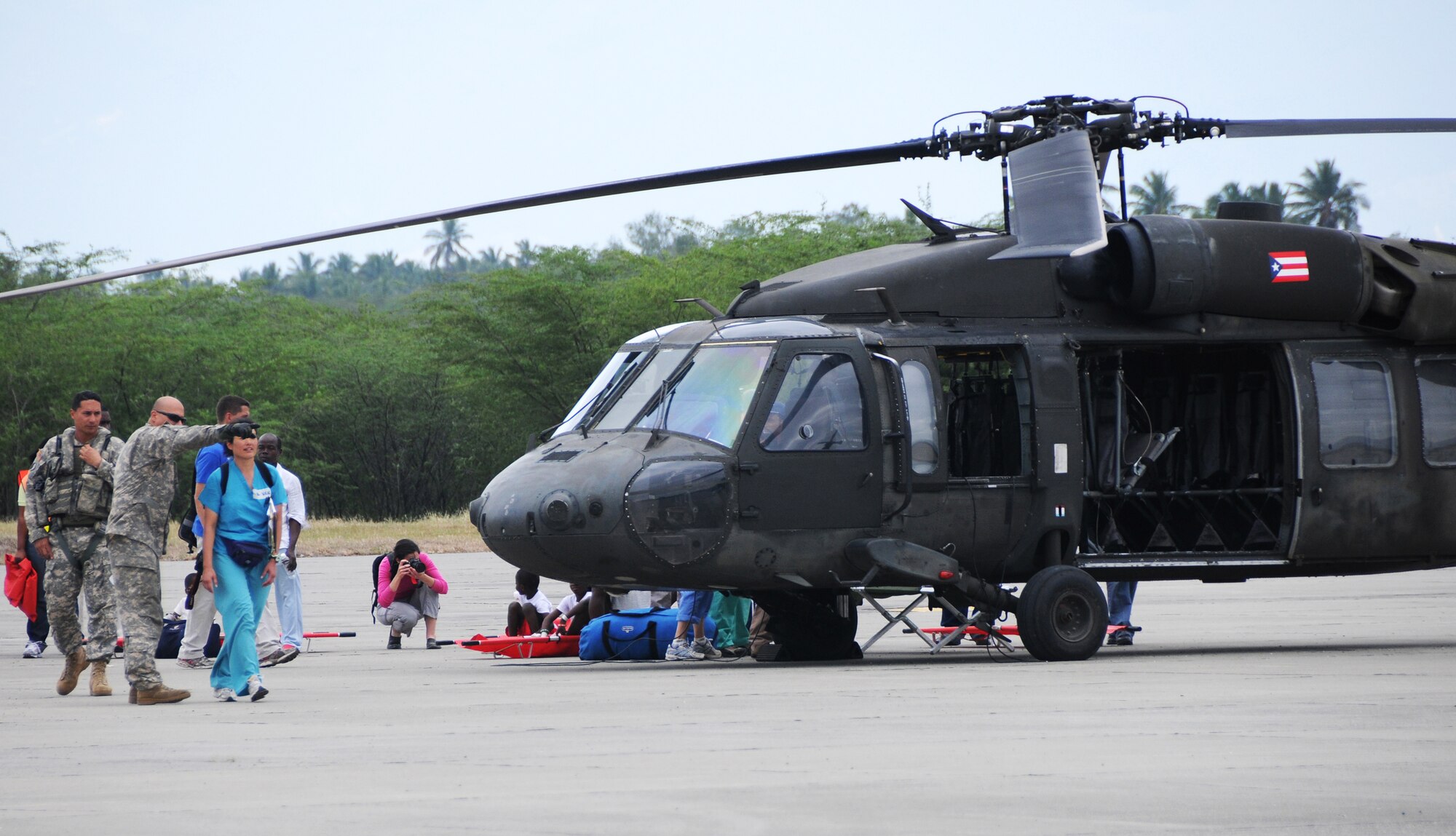 Airmen from the Kentucky National Guard's 123rd Contingency Response Group help to offload wounded Haitian refugees and medics from Puerto Rico National Guard UH-60 Black Hawk helicopters at the air hub Jan. 25, 2010, in Barahona, Dominican Republic. (U.S. Air Force photo/Tech. Sgt. Dennis Flora)