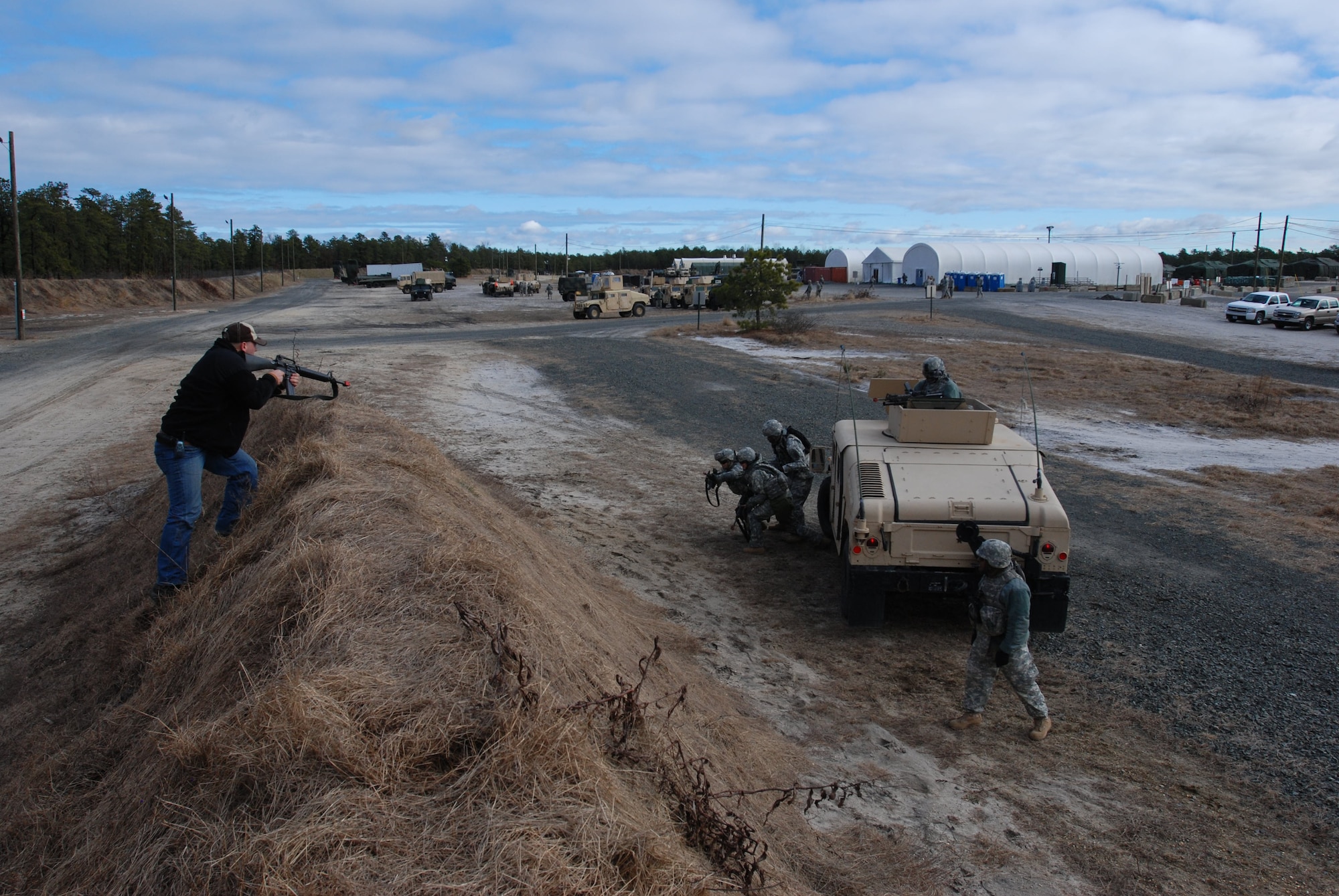 Gary Ward with the Opposing Force Cell of 2nd Battalion 309th Regiment, 72nd Field Artillery attacks U.S. Soldiers as they contuct a react to contact while mounted drill.  Sgt. Ward is providing hands-on field traing as units execute pre-mobilization training at Joint Base McGuire-Dix-Lakehurst, N.J. on Jan. 18. (U.S. Army photo by Spc. Britney Bodner)