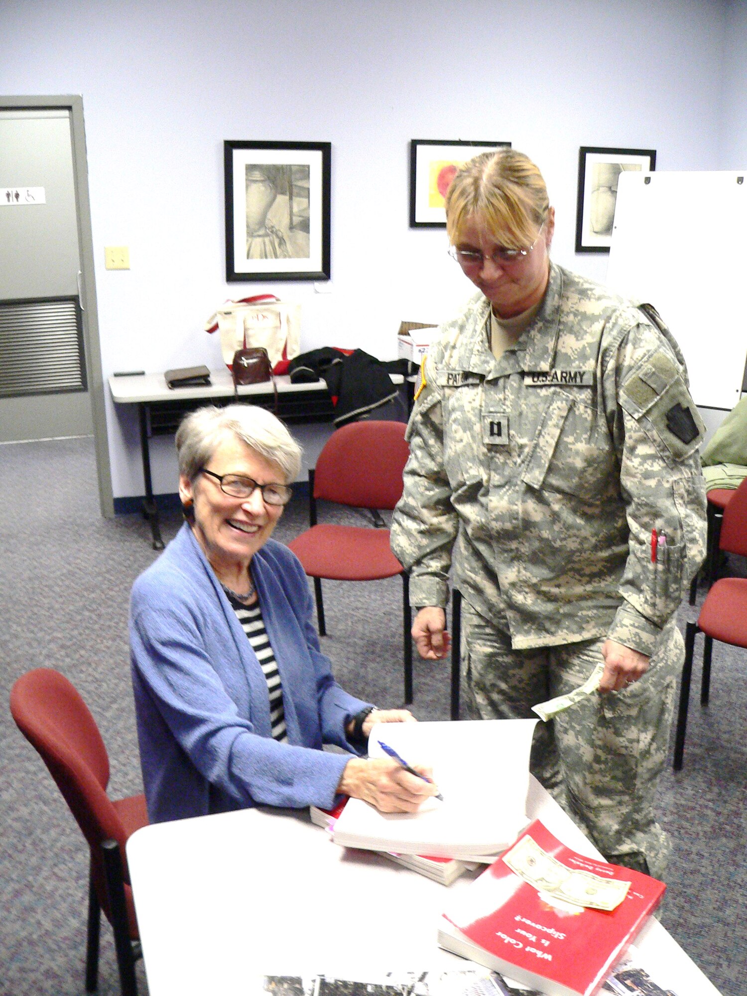 Author Denny Dalkeler signs an autograph for Capt. Sheri Patton, 56th Stryker Brigade, Pennsylvania Army National Guard at a literary reception held at the McGuire Library Jan. 20. (U.S. Air Force photo/Steve Snyder)