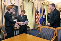 Secretary of the Air Force Michael Donley (right) looks on as the Deputy Assistant Secretary for Installations Kathleen Ferguson hands the signed proffer officially accepting the donation of a Fisher House to be built on Dover Air Force Base, Del., to the Fisher House Foundation Inc. Board of Trustees Chairman Mr. Kenneth Fisher Jan. 27, 2010, at the Pentagon. The Fisher House Foundation donates comfort homes built on the grounds of major military and Veterans Affairs medical centers. (U.S. Air Force photo/Jim Varhegyi)
