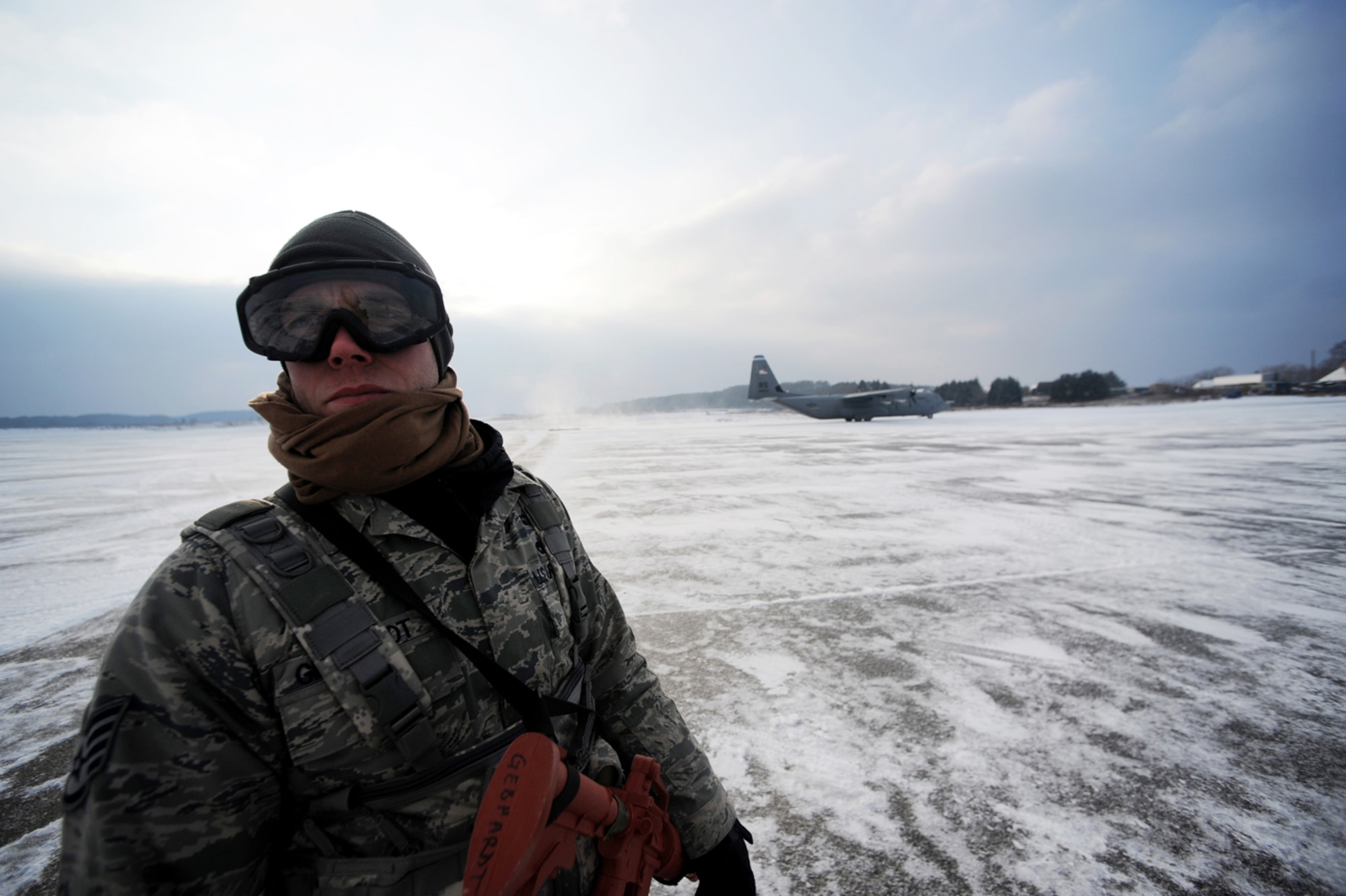 U.S. Air Force Staff Sgt. Justin Gedhardt, 435th Air Mobility Squadron, Ramstein Air Base, Germany, pulls security for a C-130 Hercules as it approaches the parking area at Flugplatz Bitburg, Germany, Jan. 26, 2010, in preparation of Ramstein's operational readiness inspection in September. The units are setting up bare-base operations as part of the dual-wing operational readiness exercise with the 86th Airlift Wing. This is the second of five operational readiness exercises. (U.S. Air Force photo by Staff Sgt. Sarayuth Pinthong)