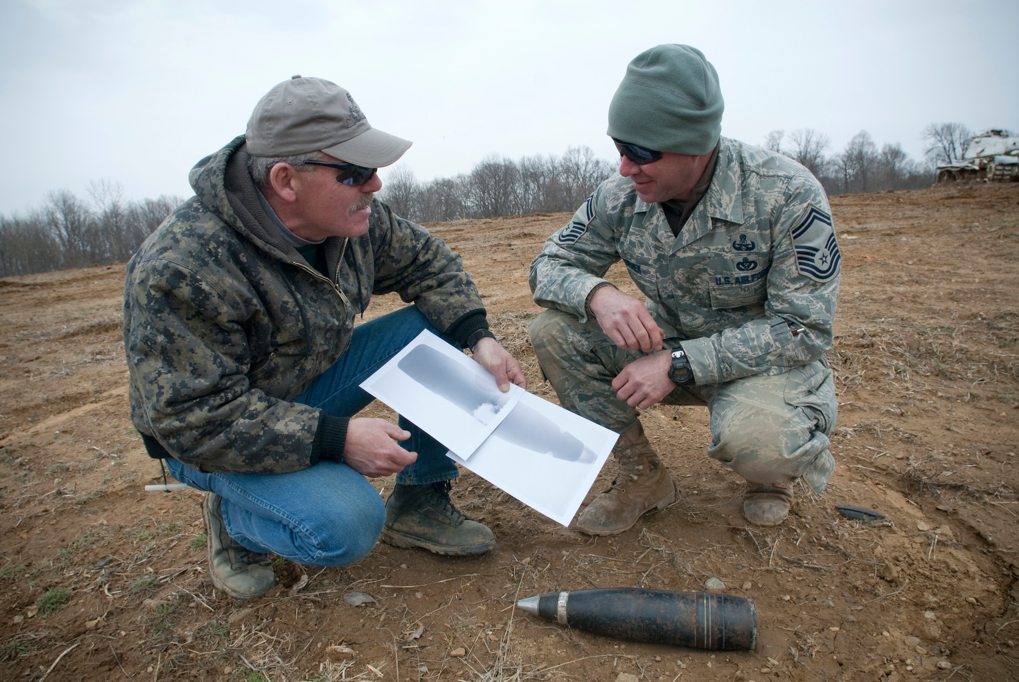 Sergeant Andy Squier, an Indiana State Police hazardous devices technician, and Senior Master Sgt. Lou Corner, Kentucky Air National Guard EOD superintendent, discuss an x-ray of a 90mm high explosive shell at the Camp Atterbury Air-to-Ground Gunnery Range, Camp Atterbury, Ind. The shell, which was turned in to the Indiana State Police and detonated by Kentucky and Indiana EOD techs, could have caused serious harm if it had exploded in a residential environment. (U.S. Air Force photo/Tech. Sgt. D. Clare)