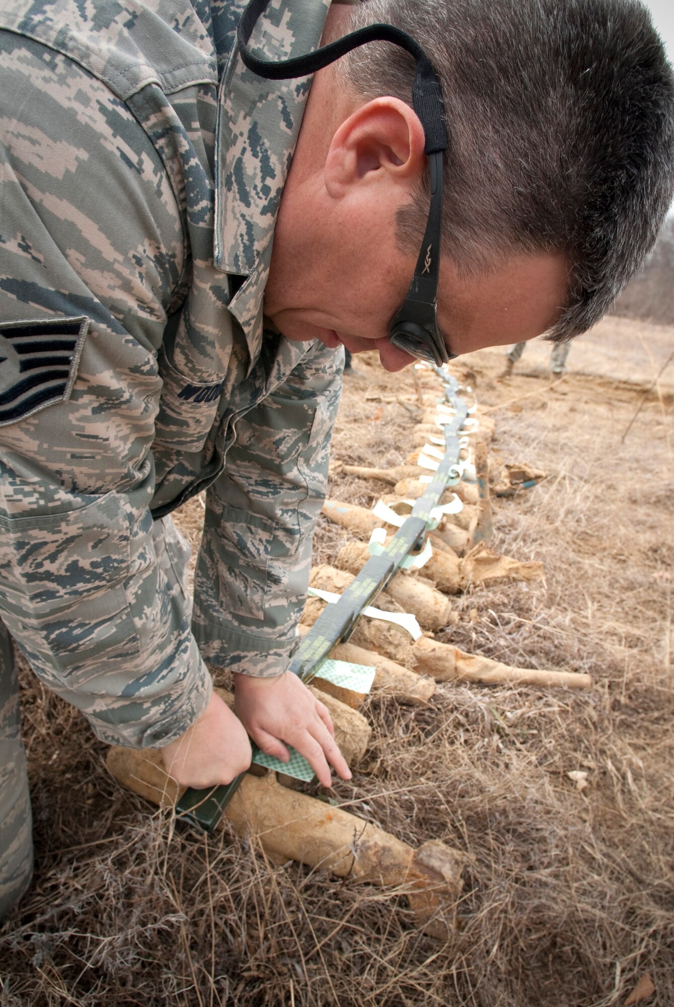 Tech. Sgt. Lowery Woods of the Kentucky Air National Guard attaches C-4 plastic explosives to a row of 25-pound practice bombs at the Camp Atterbury Air-to-Ground Gunnery Range in Indiana. (U.S. Air Force photo/Tech. Sgt. D. Clare)