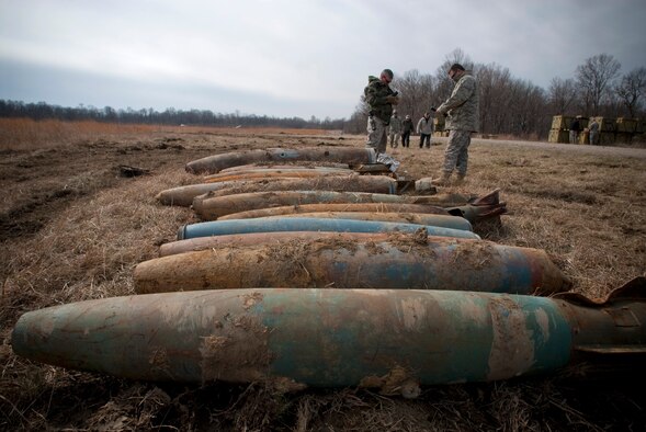Master Sgt. Shane Lagrone and Tech. Sgt. Lowery Woods of the Kentucky Air National Guard peel adhesives from C-4 plastic explosives before placing them on a long line of 500-pound practice bombs at Camp Atterbury, Ind. The ordnance, dropped by the 122nd Fighter Wing of the Indiana Air National Guard, must be recovered and inspected by explosive ordnance disposal technicians prior to entering the recycling stream. (U.S. Air Force photo/Tech. Sgt. D. Clare)