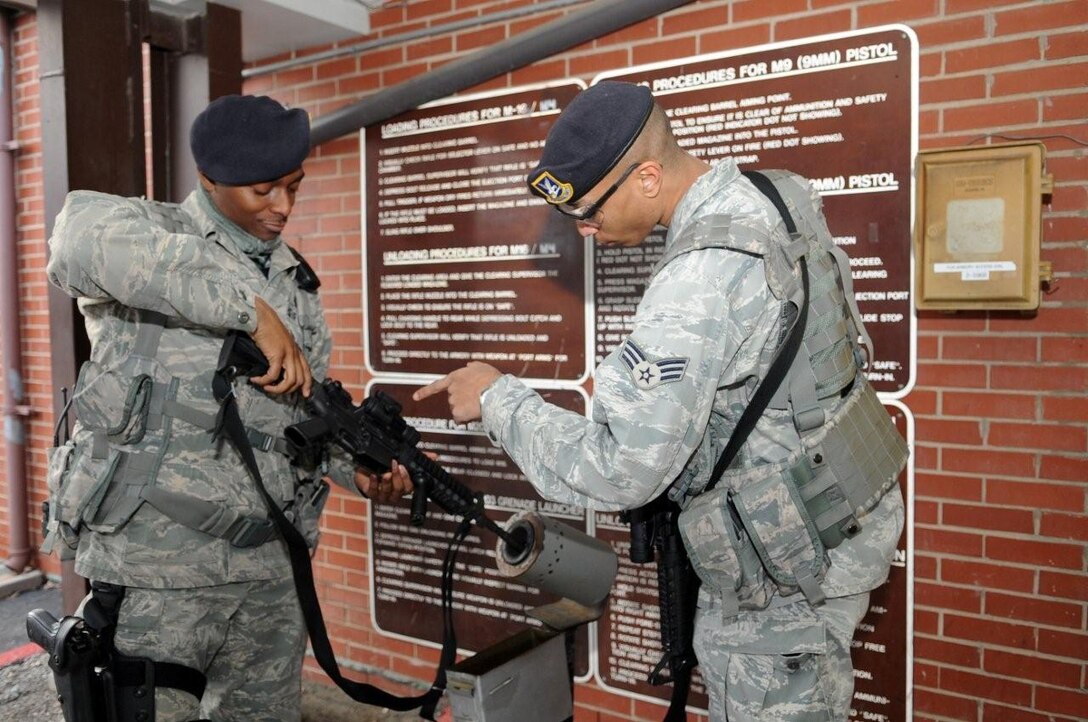 Staff Sgt. Tremayne Williams, 316th Security Forces Squadron patrolman, left, clears his M4 with the help of Senior Airman Brandon Brown, 316 SFS patrolman, right, at the 316 SFS armory Jan. 27, 2010. Airman Brown is the acting barrel clearing official who checks to ensure that the weapon is on safe and that the chamber and magazine well are both clear after shifts. The Airmen who work at the armory are responsible for issuing and accountin for more than 1500 pieces of equipment that are issued to each flight. Each day, the Airmen at the armory arm up flight patrolmen, Pinkerton Security and protective services. (U.S. Air Force photo by Airman 1st Class Melissa Rodrigues)