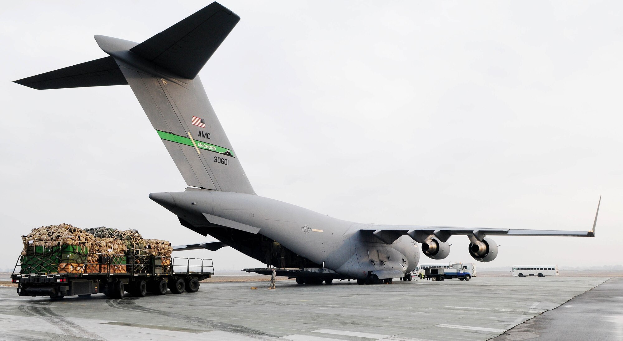 Buses arrive as more than a short ton of cargo waits on a 40K Loader prior to download on a C-17 Globemaster III at the Transit Center at Manas, Kyrgyzstan Jan. 17, 2010. Nearly 7,500 Airmen, Soldiers, Sailors and Marines along with thousands of pounds of equipment are shipped through the Transit Center every week. (U.S. Air Force photo/Senior Airman Nichelle Anderson/released) 