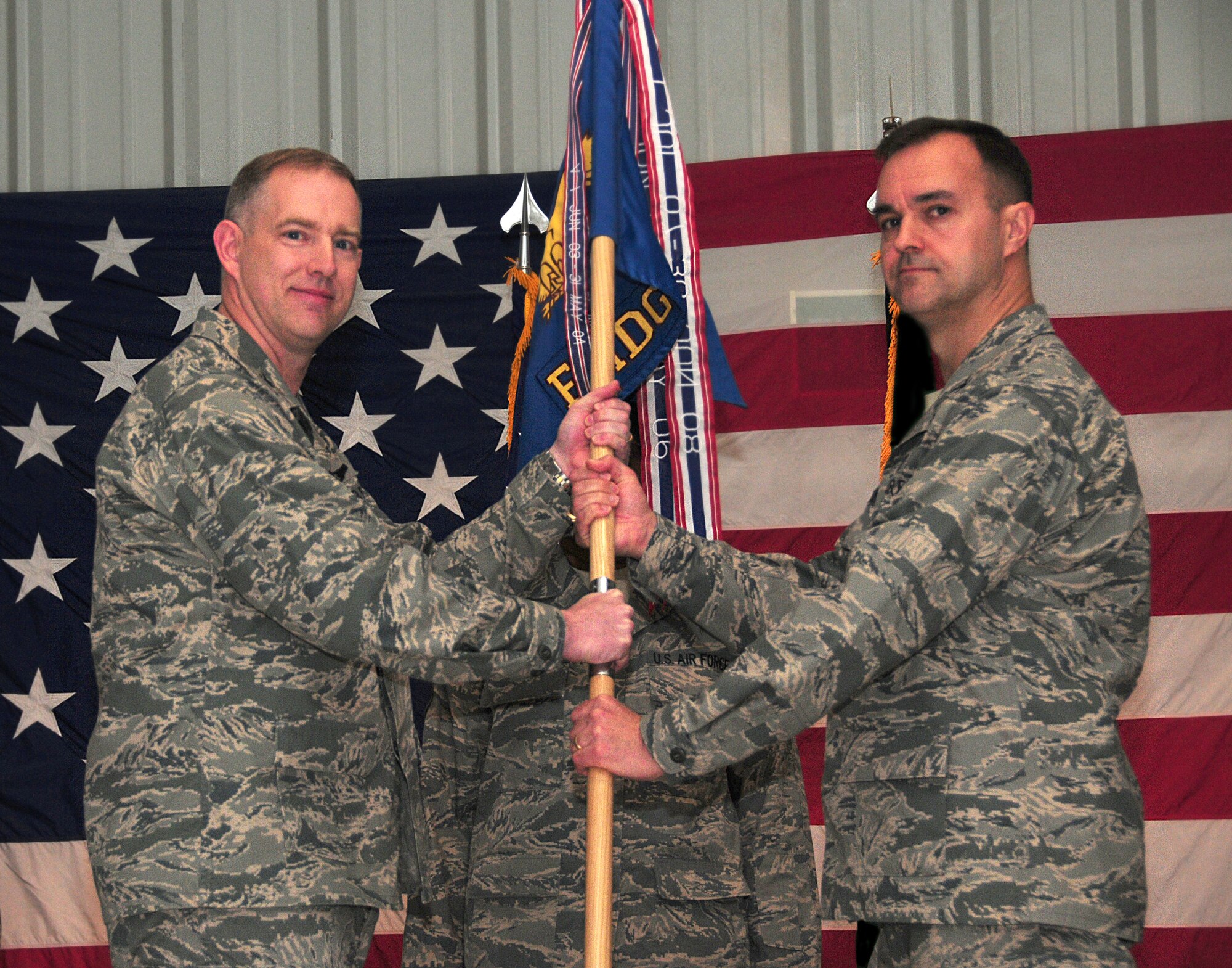 Col. John R. Gordy II, 386th Air Expeditionary Wing commander, passes the 386th Expeditionary Medical Group guidon to Col. Michael Schaffrinna, 386th EMDG commander, during the unit change of command ceremony Jan. 29, 2010 at an air base in Southwest Asia. (U.S. Air Force photo illustration by Staff Sgt. Lakisha A. Croley/Released)
