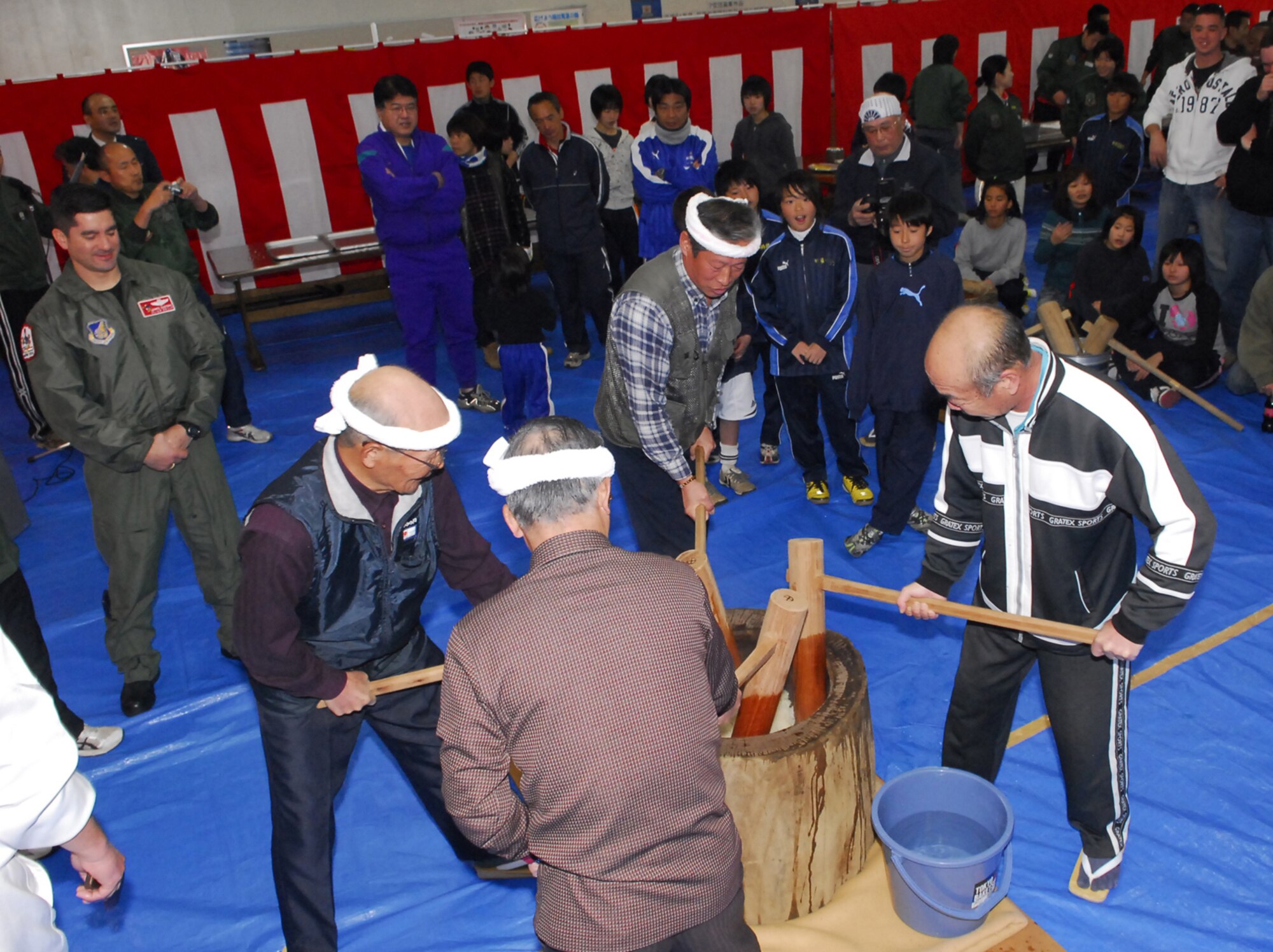 Gentlemen from neighboring towns in Iberaki Prefecture, north of Tokyo, take the first step of stirring and kneading the rice into a more maleable consistency at the Mochitsuki celebration Jan. 30. Mochi is a traditional food for the Japanese New Year and is commonly sold and eaten during that time. Airmen from Hyakuri Air Base and members of the local community invited the U.S. Air Force Airmen to participate in the event. (U.S. Air Force / 1st Lt. Bryan Bouchard)