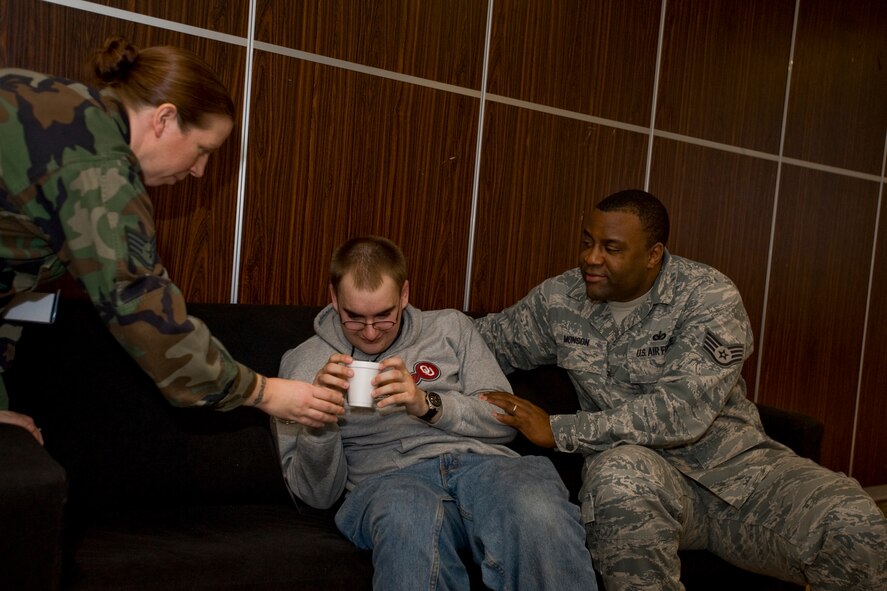 MISAWA AIR BASE, Japan -- Staff Sgt. Michelle Whitley, 35th Medical Support Squadron laboratory technician, and Staff Sgt. Kendrick Monson, 35th Security Forces Squadron NCO in charge of customs, consoles Senior Airman Drew Joslin, 35th Communications Squadron systems technician, during the noncombatant evacuation operations scenario Jan. 28 at the Mokuteki ballroom. In the scenario, Airman Joslin played the role of a hyper-active 3-year-old. (U.S. Air Force photo/Senior Airman Jamal D. Sutter)