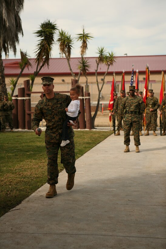 Sgt. Maj. Antonio N. Vizcarrondo Jr. holds his grand daughter as he speaks to Marines and sailors of 1st Marine Logistics Group during his acceptance speech after being appointed 1st MLG Sergeant Major.
