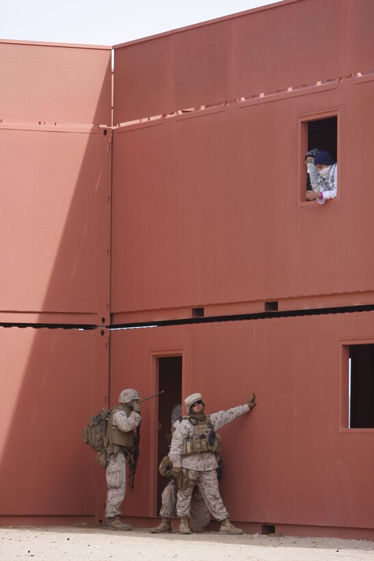 Afghan role players watch Marines from Company K, 3rd Battalion, 1st Marine Regiment, from Marine Corps Base Camp Pendleton, Calif., as they search the building below them Jan. 31. The battalion recently completed their Enhanced Mojave Viper here at Combat Center Range 220.
