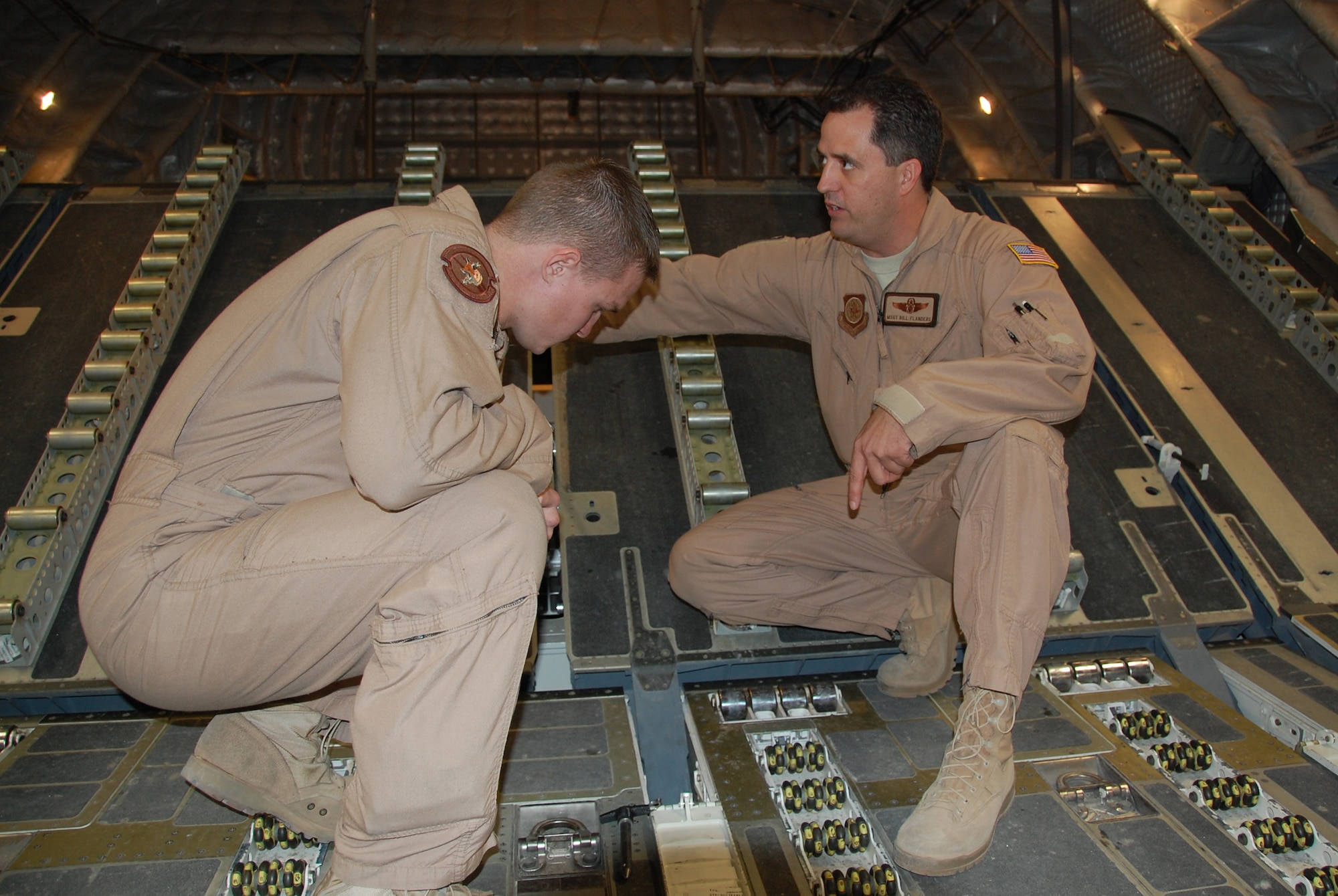 U.S. Air Force Master Sgt. Bill Flanders, 817th Expeditionary Airlift Squadron C-17 loadmaster, shows Senior Airman Daniel McClain, 737th EAS C-130H loadmaster, some of the differences between their respective planes Jan. 30, 2010 during the Quarry Open House at an air base in Southwest Asia. (U.S. Air Force photo by Staff Sgt. Lindsey Maurice/Released)