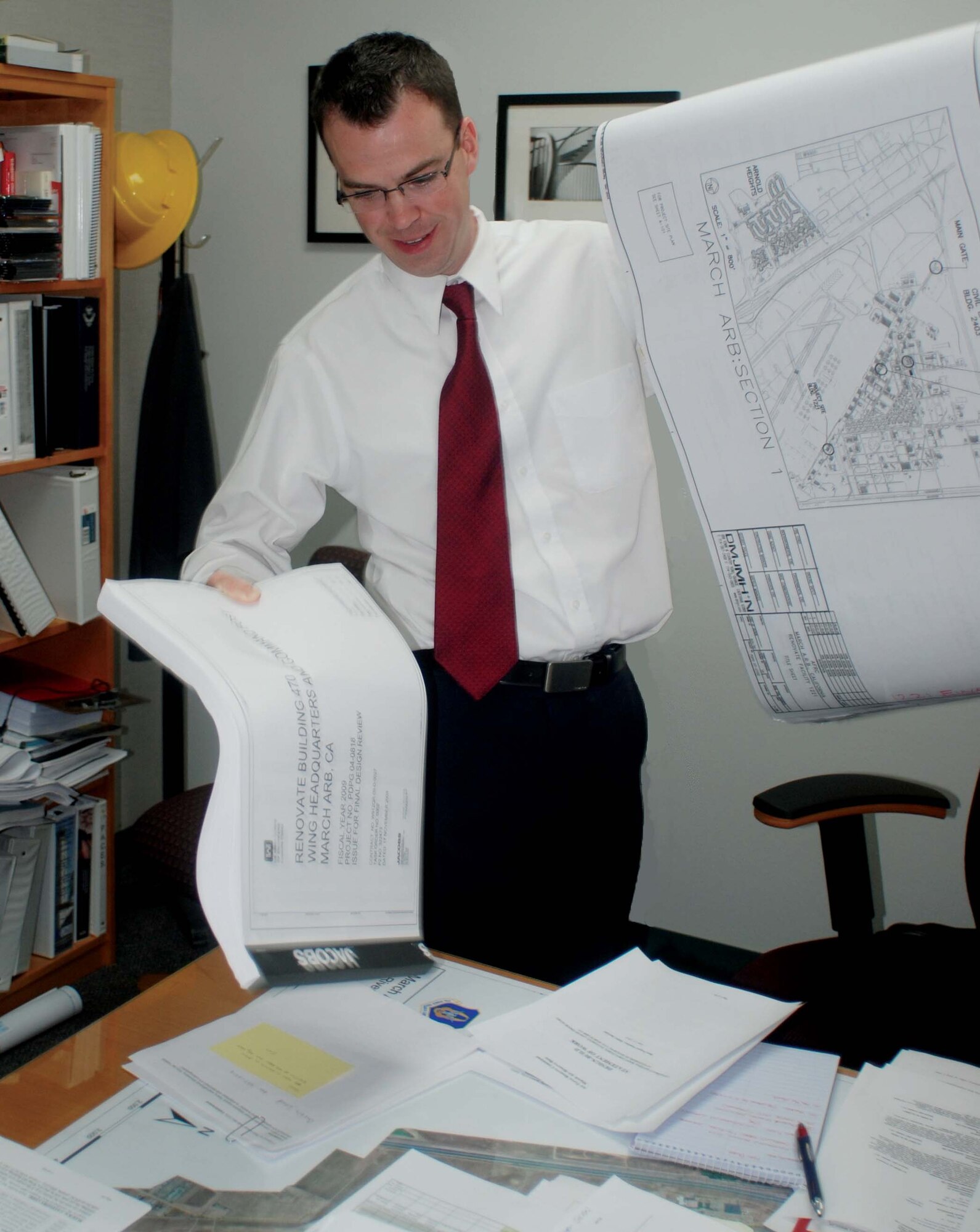 Sean Feeley, 452nd Civil Engineering chief engineer, places the plans for the renovation of the base headquarters building on his desk, June 17. Construction for the project will begin toward the end of the year.  (U.S. Air Force photo by Megan Just)
