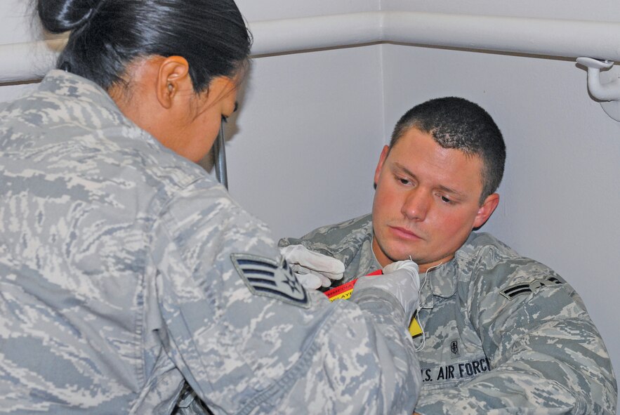 Staff Sgt. Shella Mae Valdez, 56th Medical Group medical technician, marks a triage card for Airman 1st Class David Valois, 56th Medical Support Squadron member, June 24th after he was injured by blown out windows caused by a microburst on the second floor of the 56th MDG building during exercise Crown Talon 10-2. (U.S. Air Force photo by Senior Airman Tracie Forte)